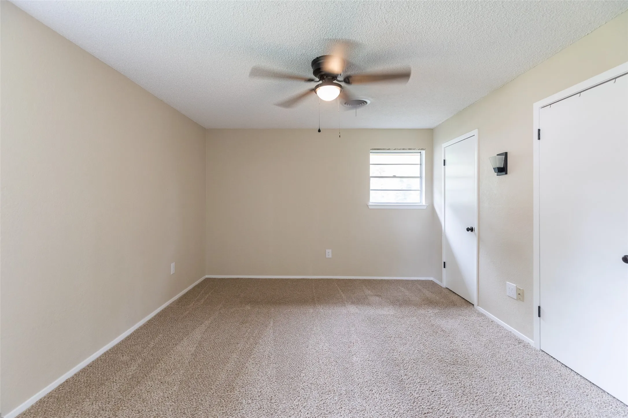 Carpeted room featuring neutral-toned walls, a ceiling fan with integrated lighting, and a single window