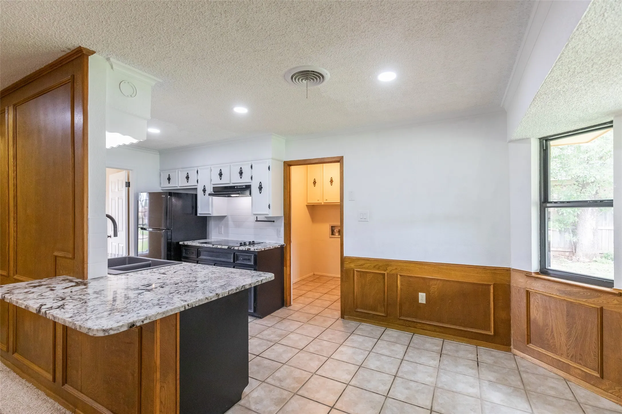 Kitchen featuring granite countertops, wood paneling, tiled flooring, recessed lighting, and a built-in electric cooktop