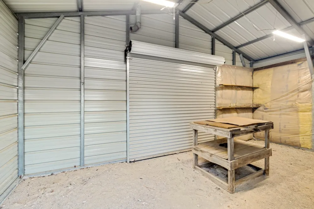 Shop on back side of farm equipment covered parking with elect. and an insulated roll up door.