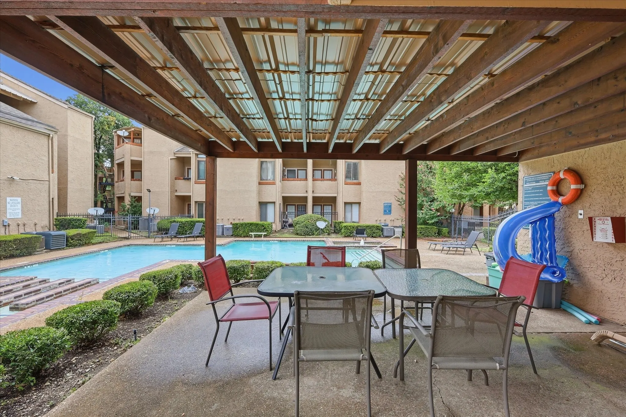Covered patio area featuring a slatted wooden pergola and concrete flooring