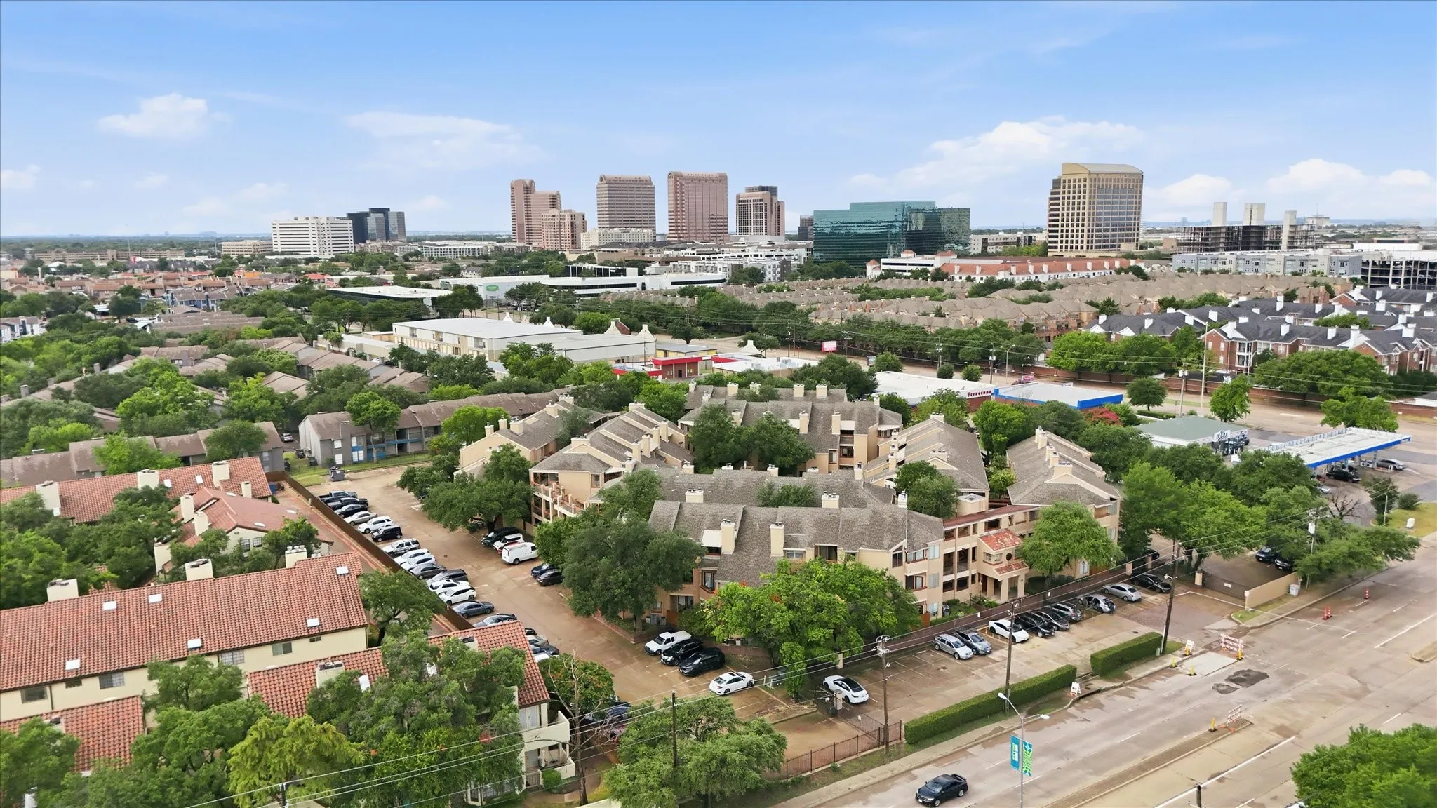 Aerial perspective showcasing multiple residential buildings with terracotta-style roofs and surrounding mature trees