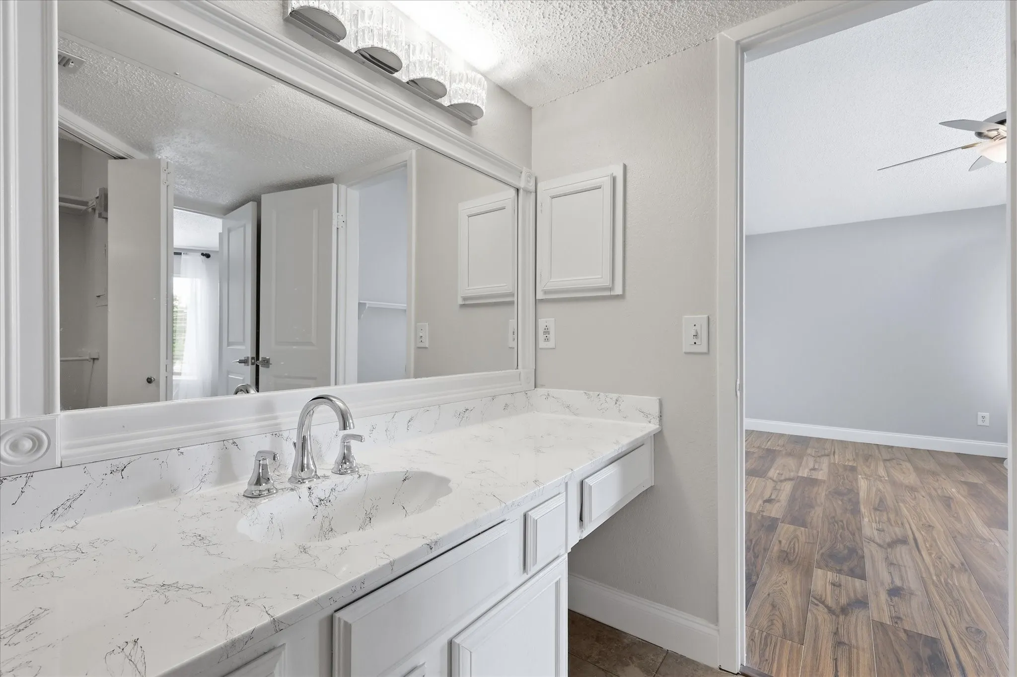 Bathroom vanity featuring a polished chrome faucet, white countertop with integrated sink, and a large framed mirror