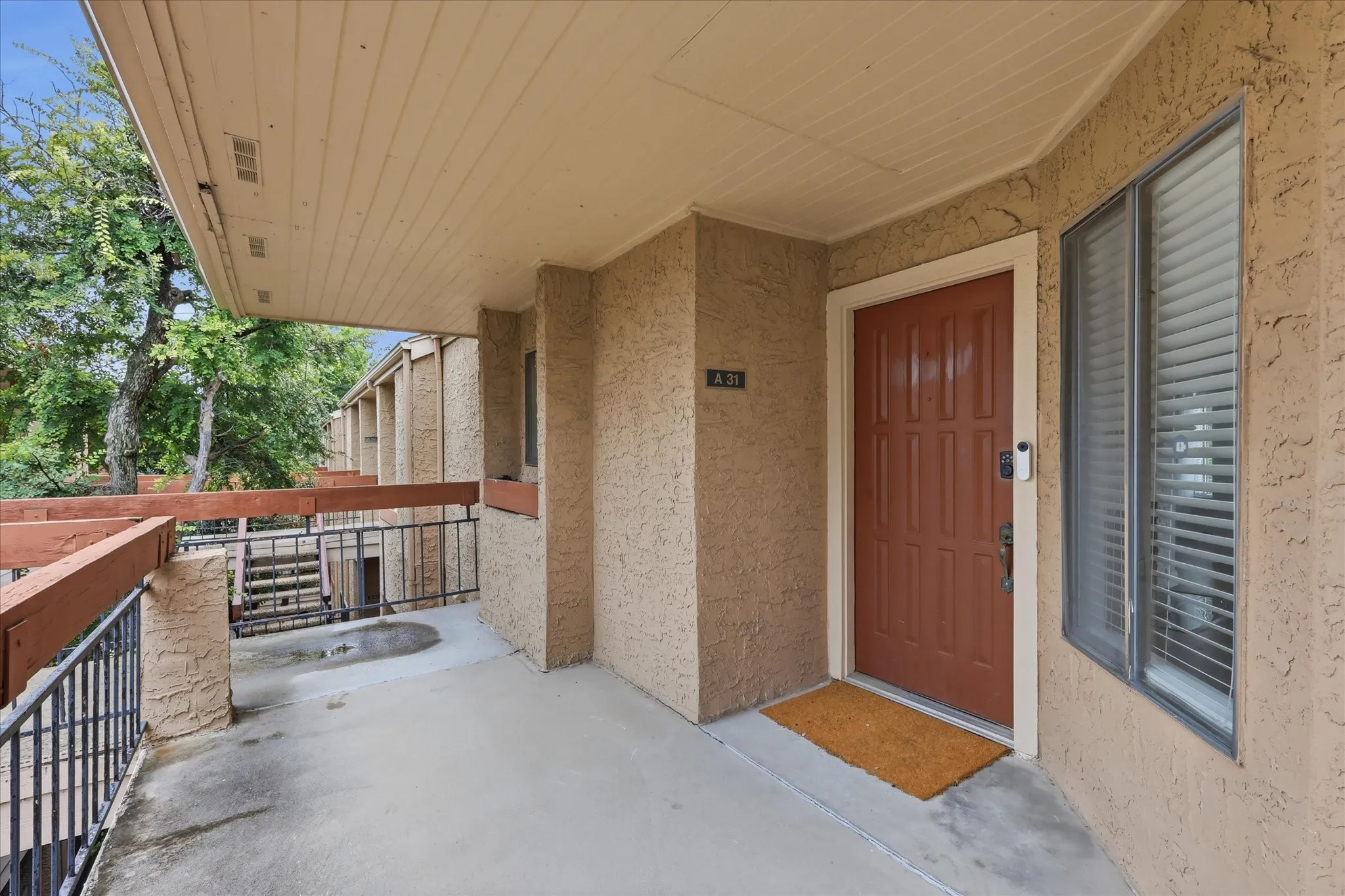 Covered entry with textured stucco exterior, an insulated paneled door, and a multi-pane window with blinds