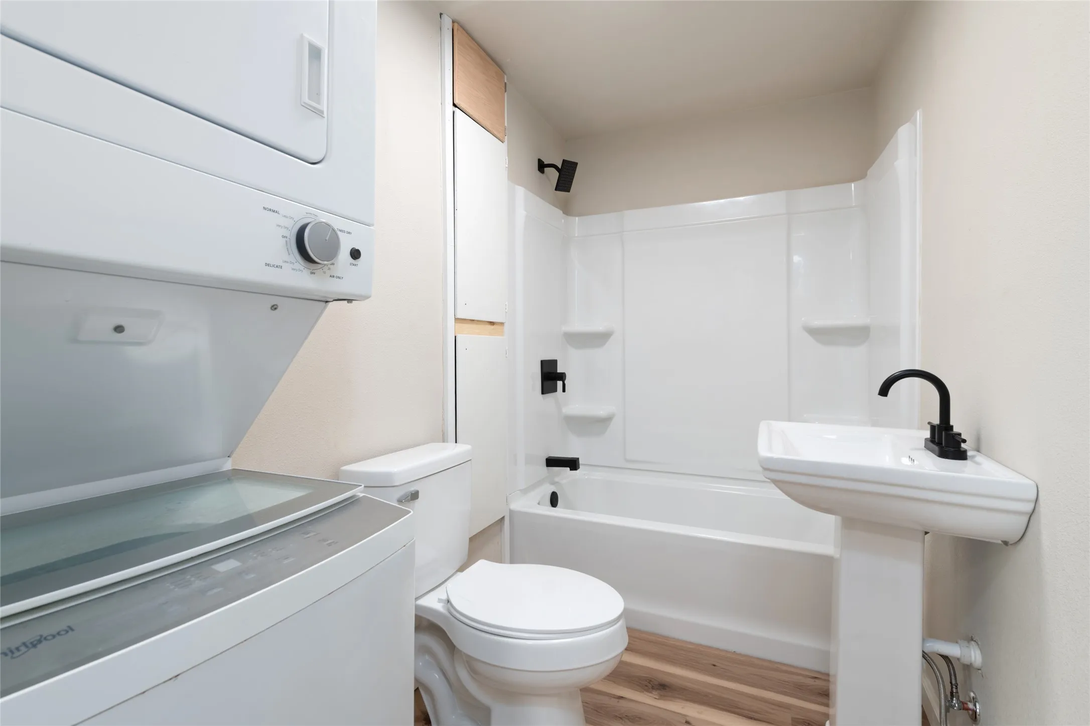 Full bathroom featuring a white pedestal sink with a matte black faucet, a white toilet, and a combined tub and shower with matte black fixtures