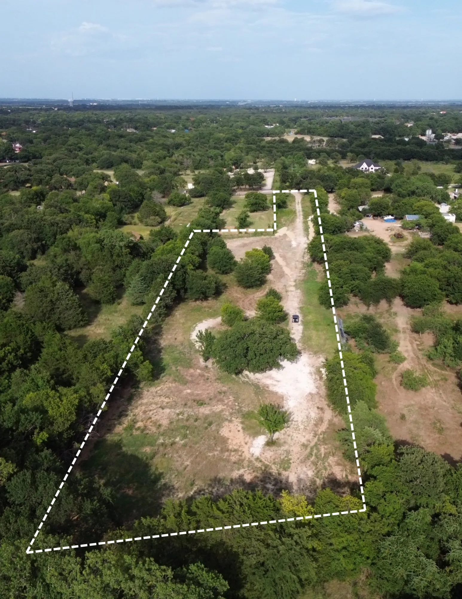 Expansive land parcel featuring mature trees and a cleared central path