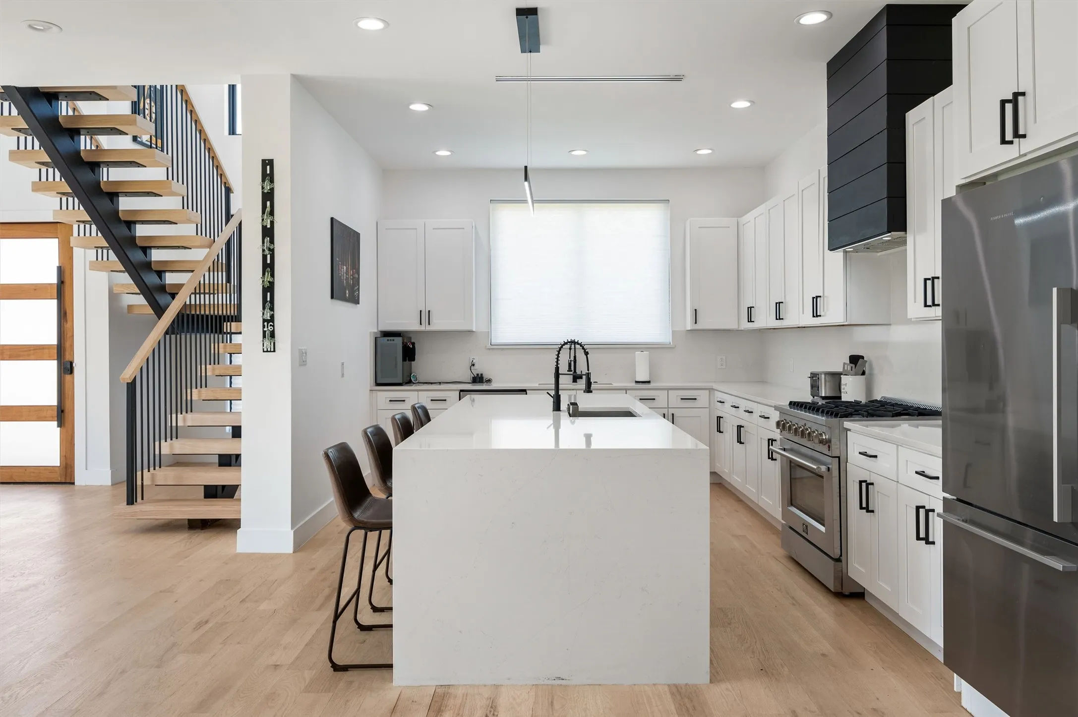 Beautifully Appointed Kitchen Offering A Dramatic Waterfall Island, Custom Shaker Cabinetry, Stainless Steel Appliances, Designer Lighting, And Seating For Family And Guests.