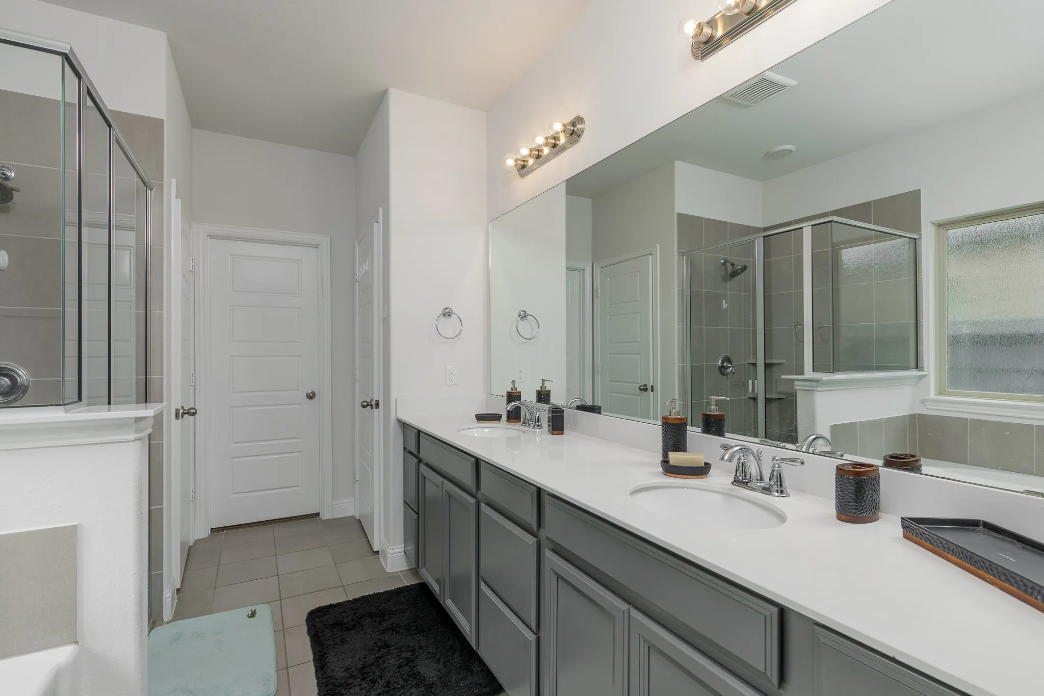 Bathroom featuring a double vanity with white countertops, gray cabinetry, and dual undermount sinks