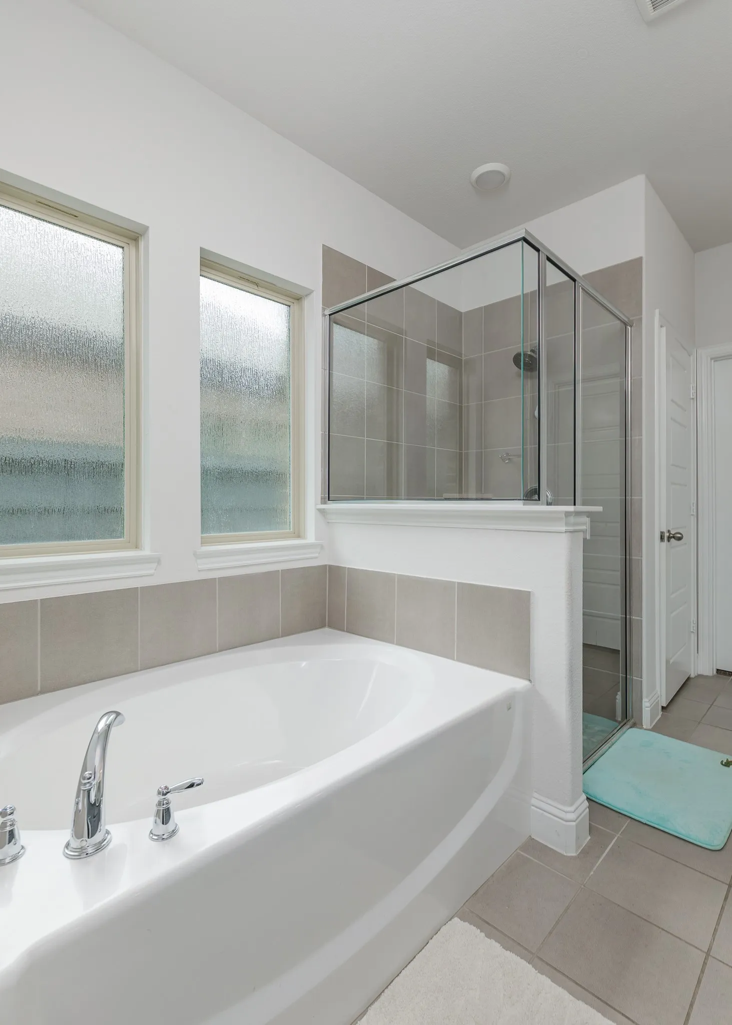 Soaking tub with chrome fixtures and surrounding tile accent wall