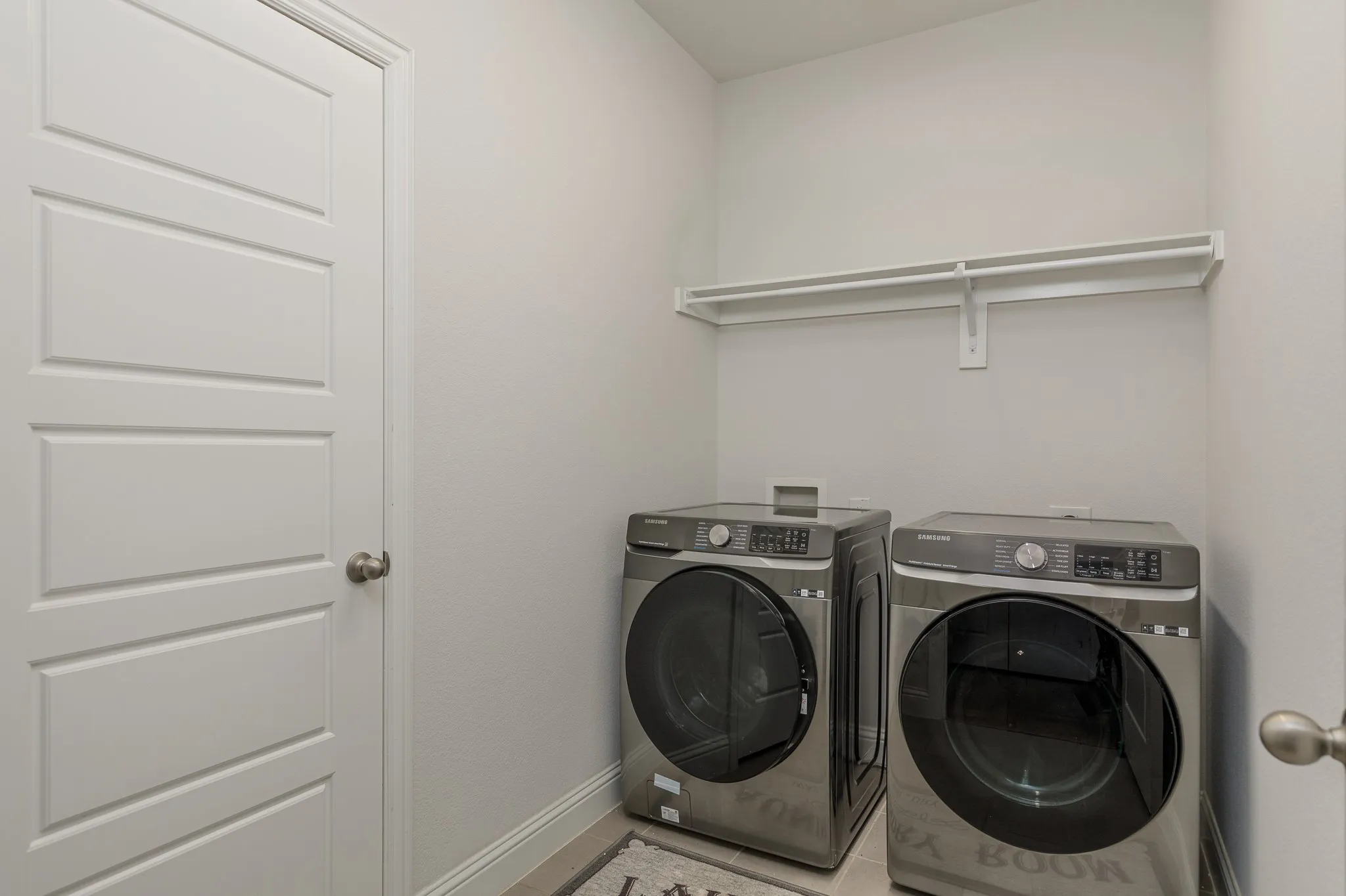 Dedicated laundry area featuring light gray wall paint and a white four-panel door with brushed nickel hardware
