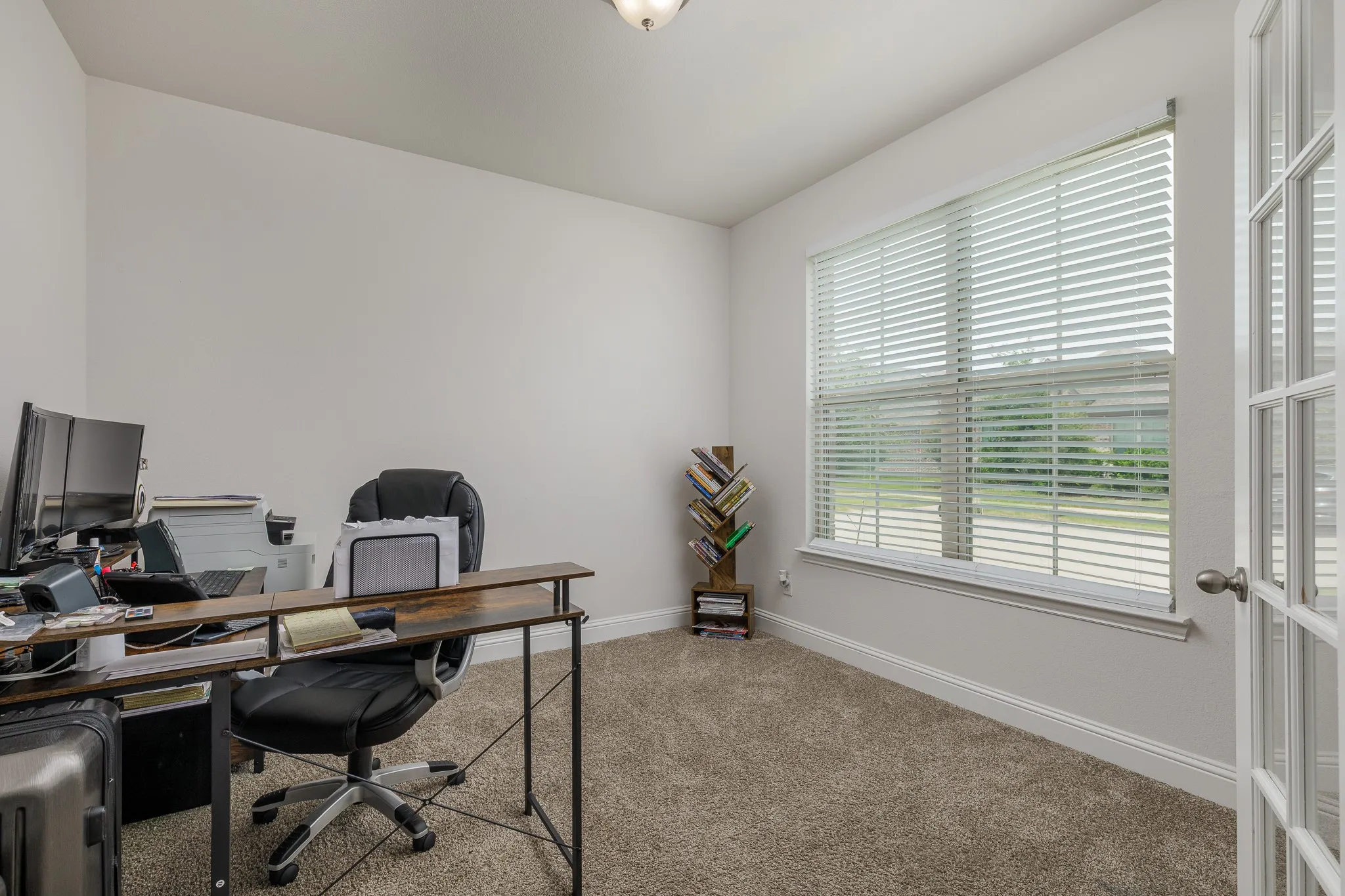 Carpeted room with a large window featuring blinds
