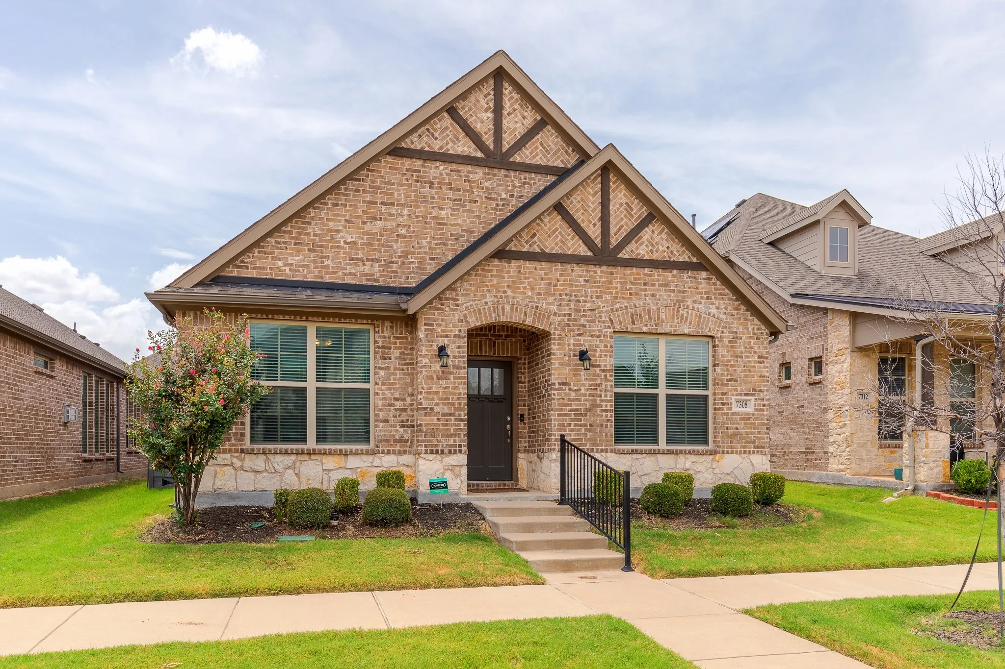 Brick and stone facade featuring a prominent gable with decorative wood-look trim