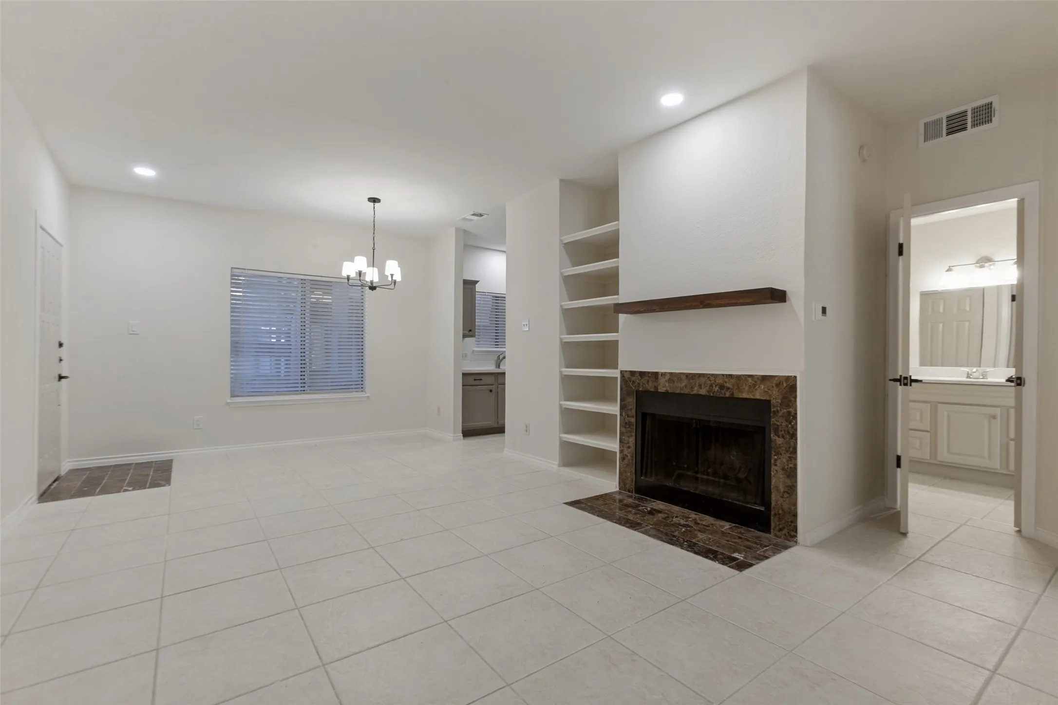Living area featuring a fireplace with a stone surround, built-in shelving, and tile flooring