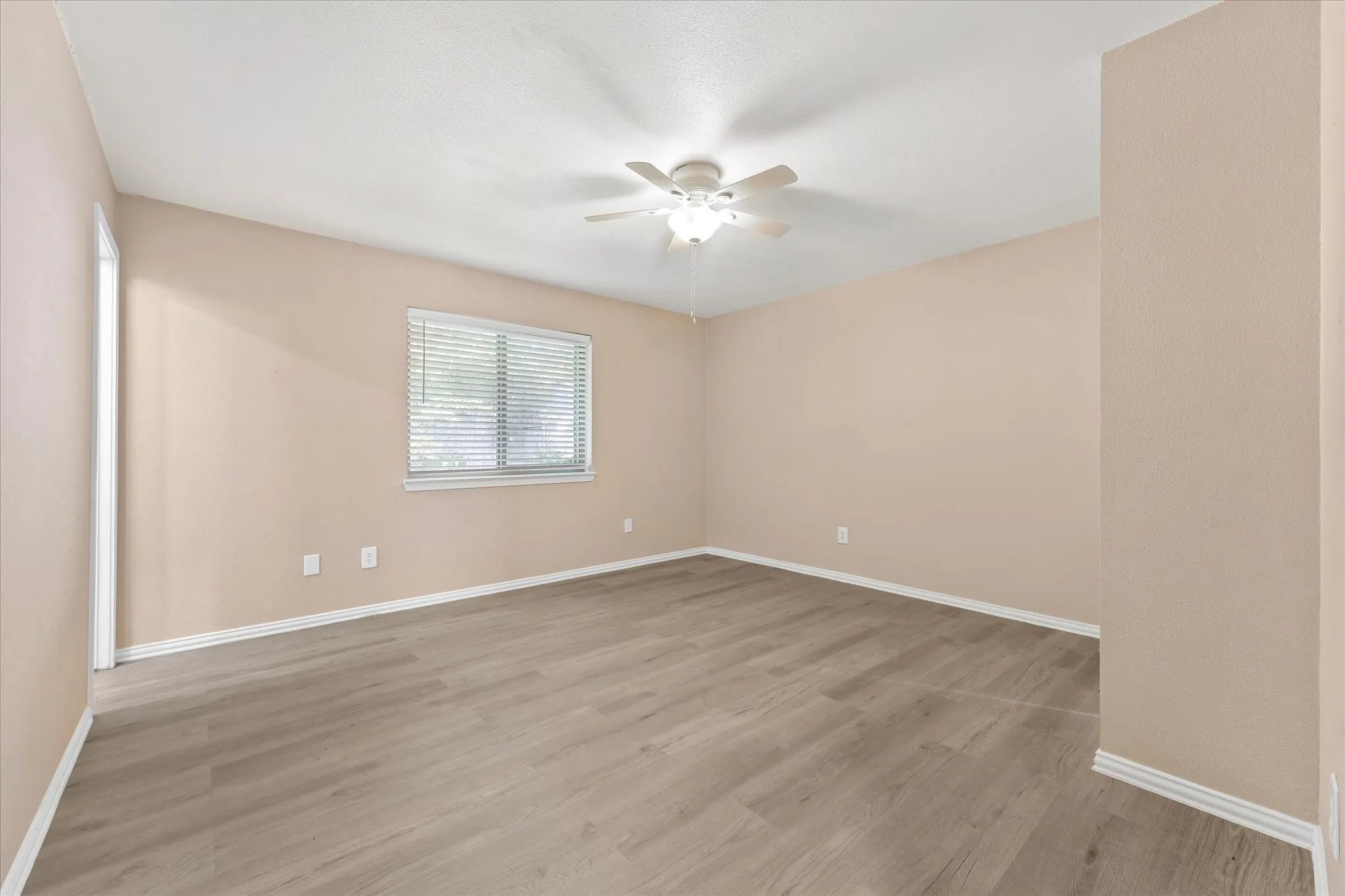 Master bedroom with neutral-toned walls, wood-finish LVP flooring, and a ceiling fan with integrated lighting