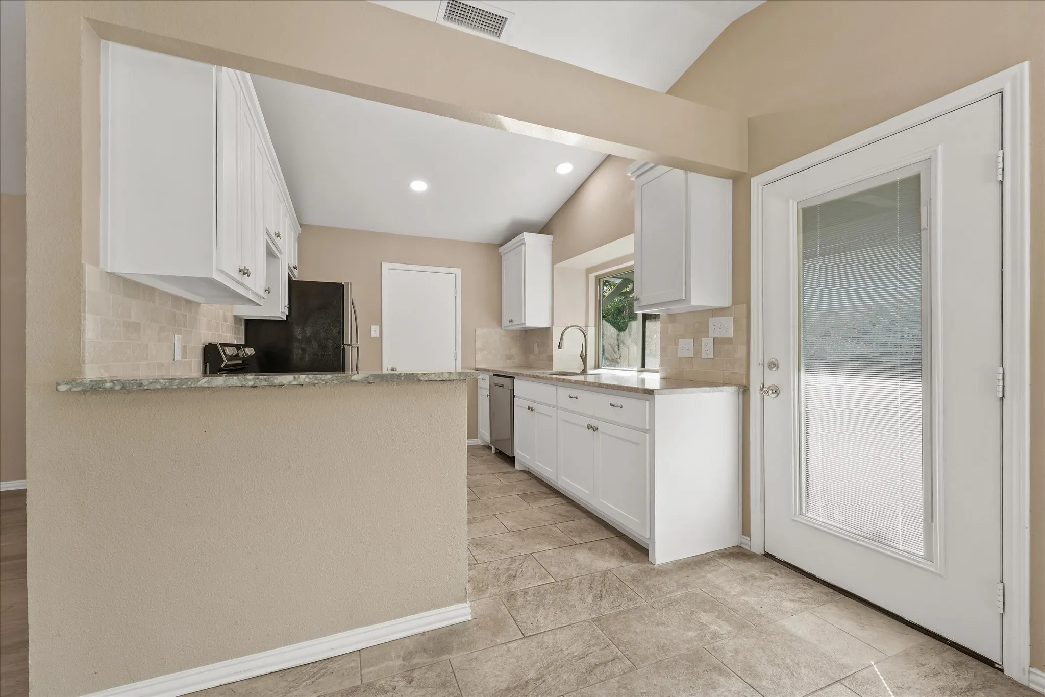 Kitchen featuring white cabinetry, light-toned tile flooring, light-colored quartz countertops, a tile backsplash, and a glass-paneled exterior door