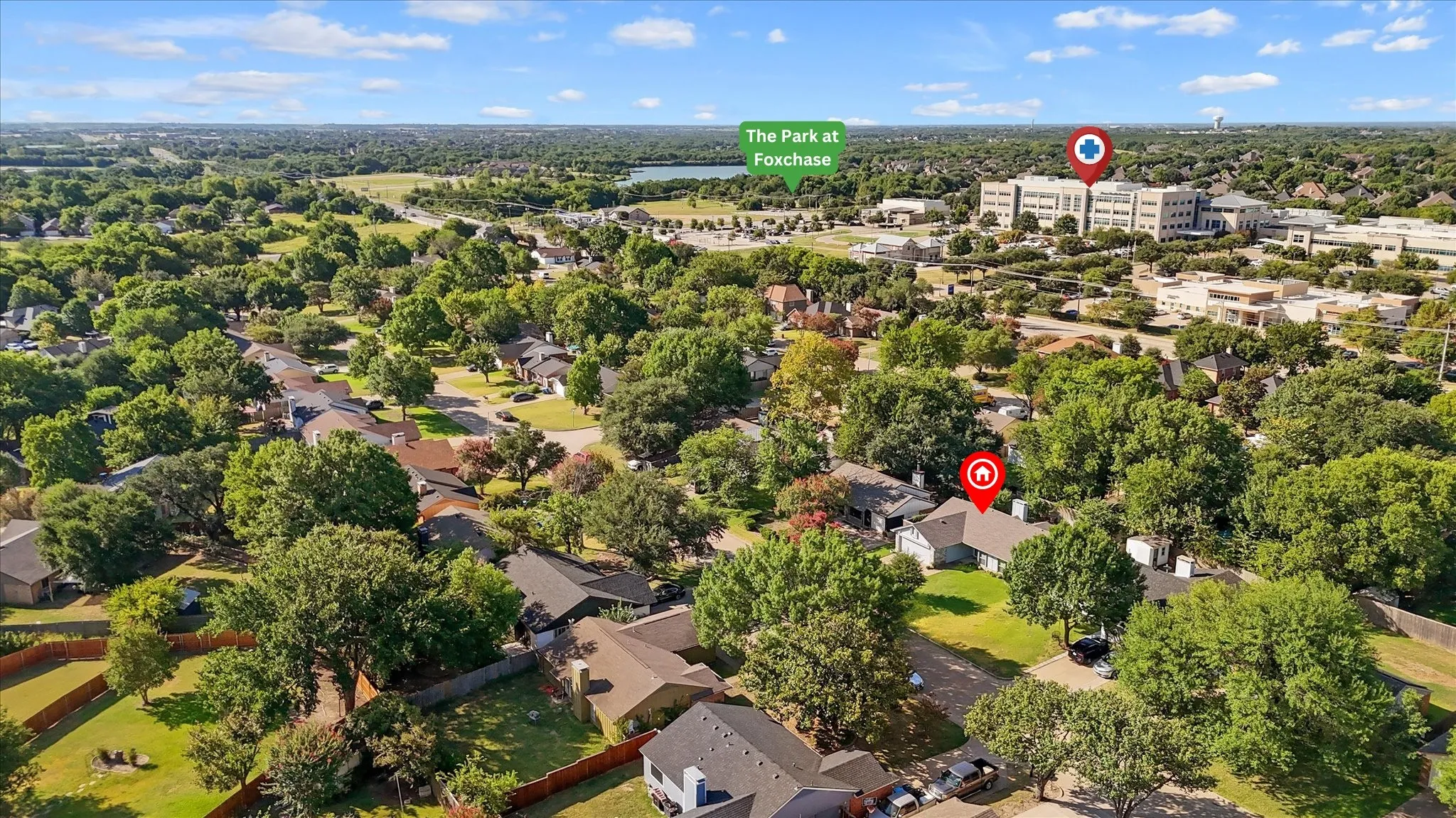 Aerial perspective showcasing residential neighborhood with mature trees, green spaces, and hospital.