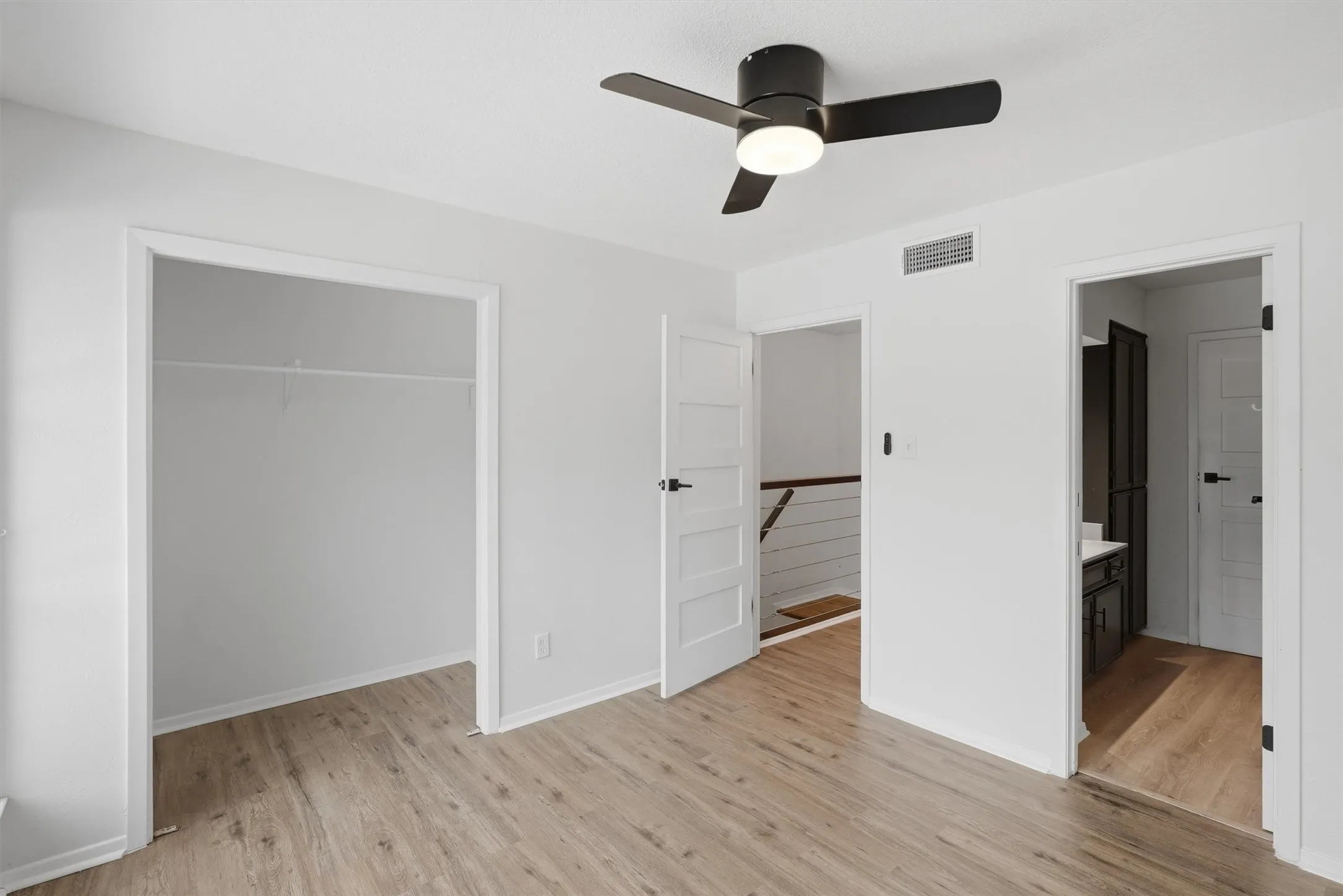 Room featuring wood-finish flooring, a ceiling fan with integrated lighting, and a closet with wire shelving