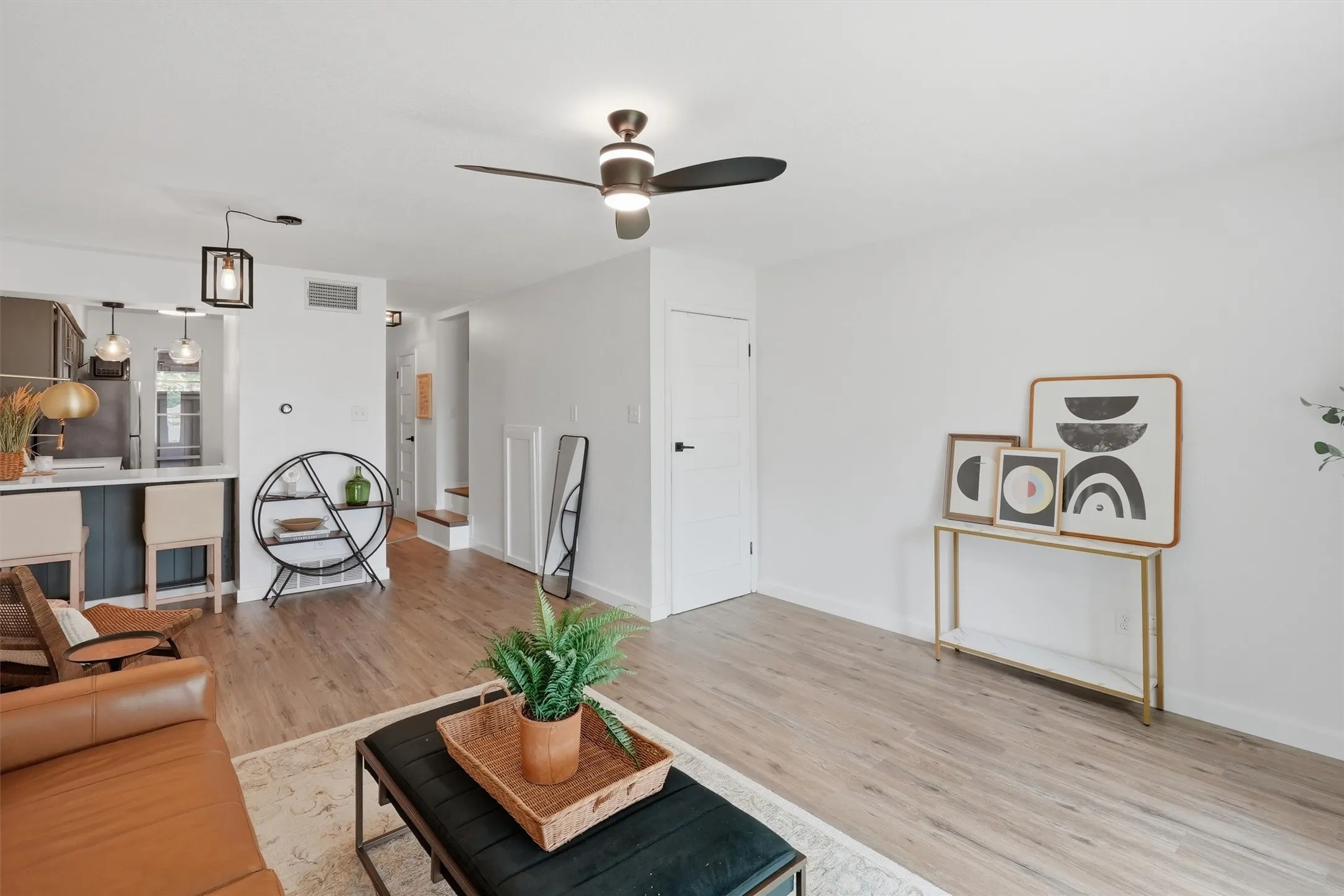 Open-concept living area featuring wood-finish flooring, a contemporary ceiling fan, recessed lighting, and a white interior door with dark hardware