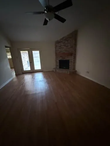 Living space featuring wood-finish flooring, a ceiling fan, and a brick fireplace