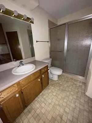 Bathroom featuring a single vanity with wood-finish cabinetry, a white oval sink, and a gray countertop