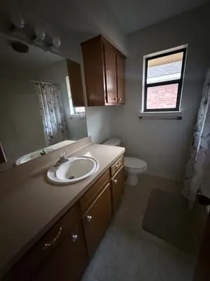 Bathroom featuring a spacious vanity with an integrated sink, a large mirror, and wood-finish cabinetry