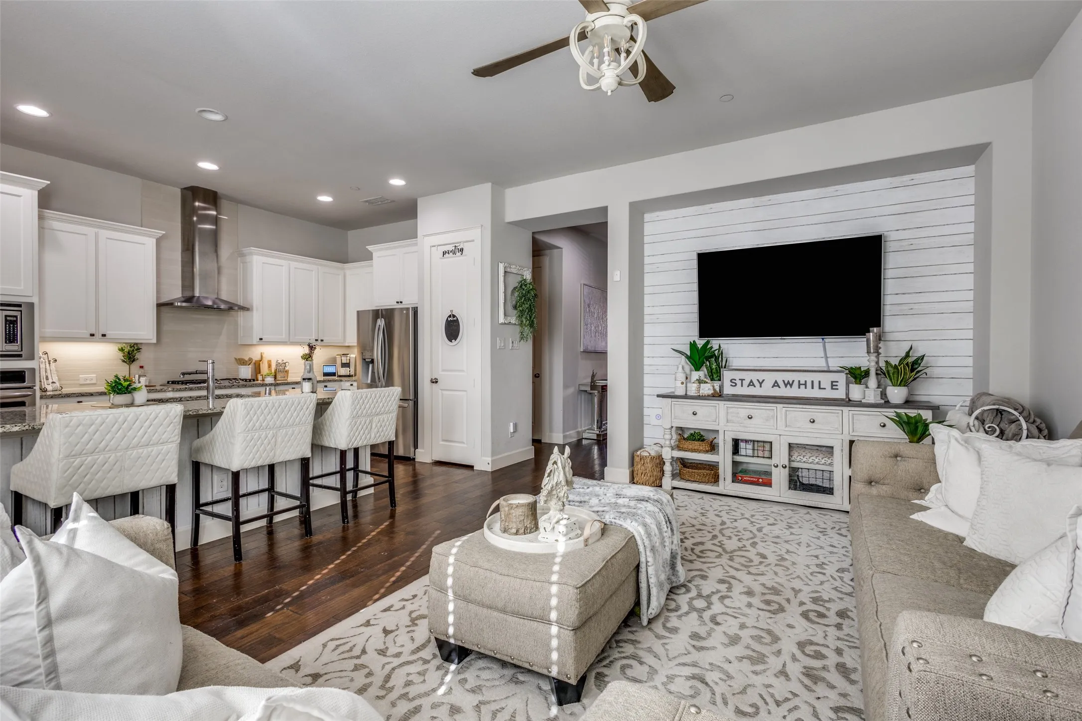 Open-concept living space featuring a modern kitchen with white cabinetry, stainless steel appliances, and a breakfast bar