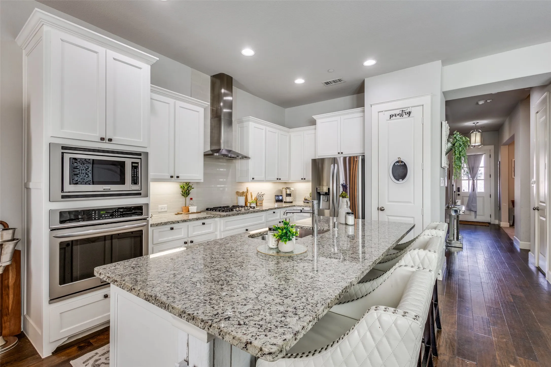 Kitchen featuring white shaker cabinetry, stainless steel appliances, a large island with a granite countertop, and wood-finish flooring