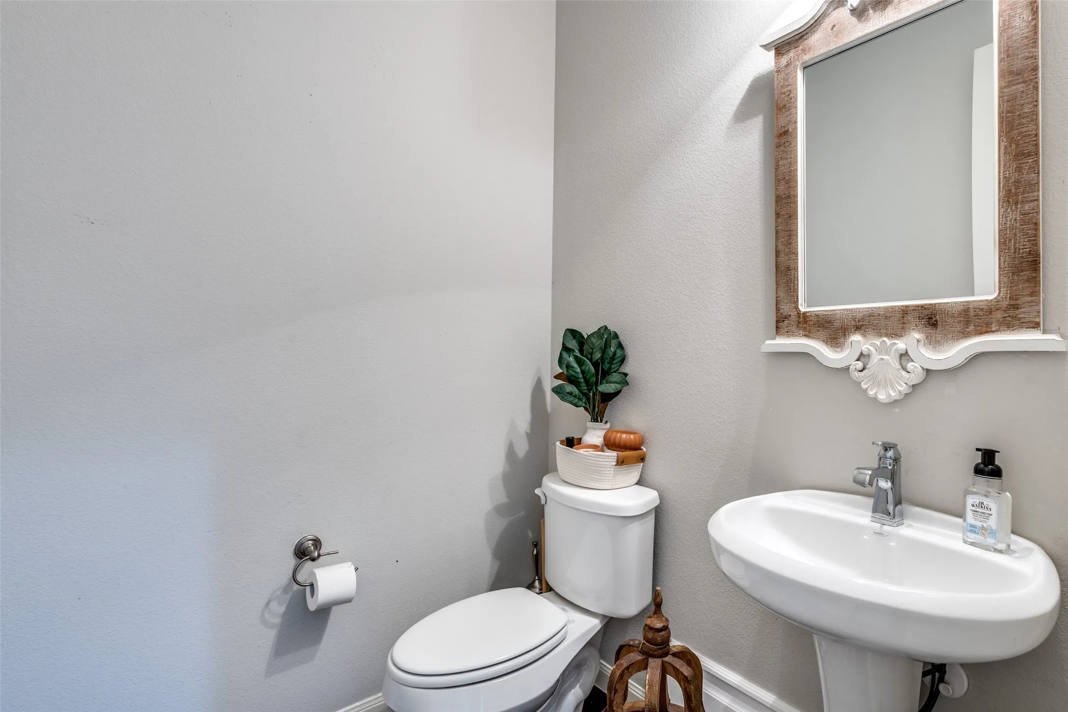 Pedestal sink with chrome faucet, framed mirror, and toilet