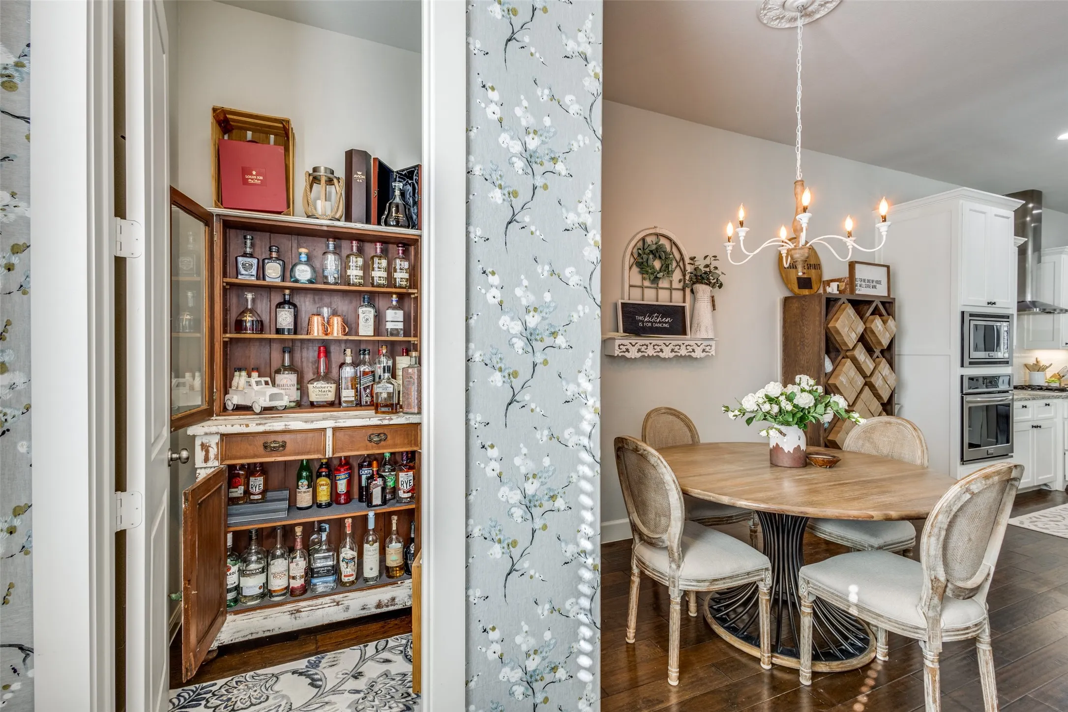 Dining area featuring a wood-finish oval table with a black metal base, and a white chandelier with candle-style lights