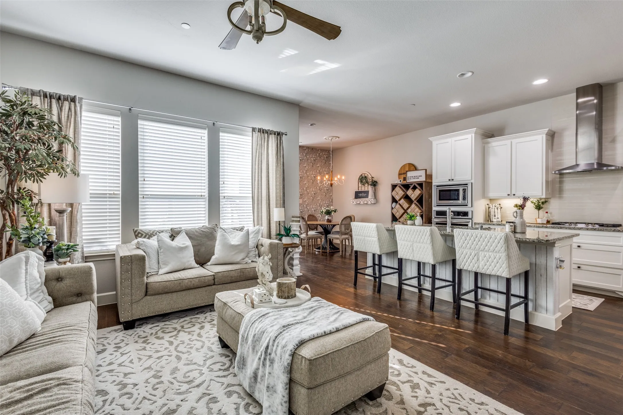 Open-concept living space featuring wood-finish flooring, a contemporary ceiling fan, and a kitchen island with seating