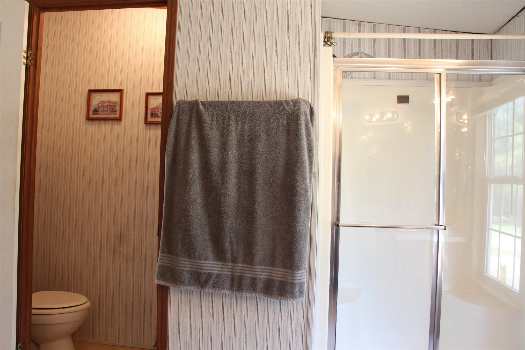 Full bathroom featuring a stand-up shower with a clear glass enclosure and a separate commode area