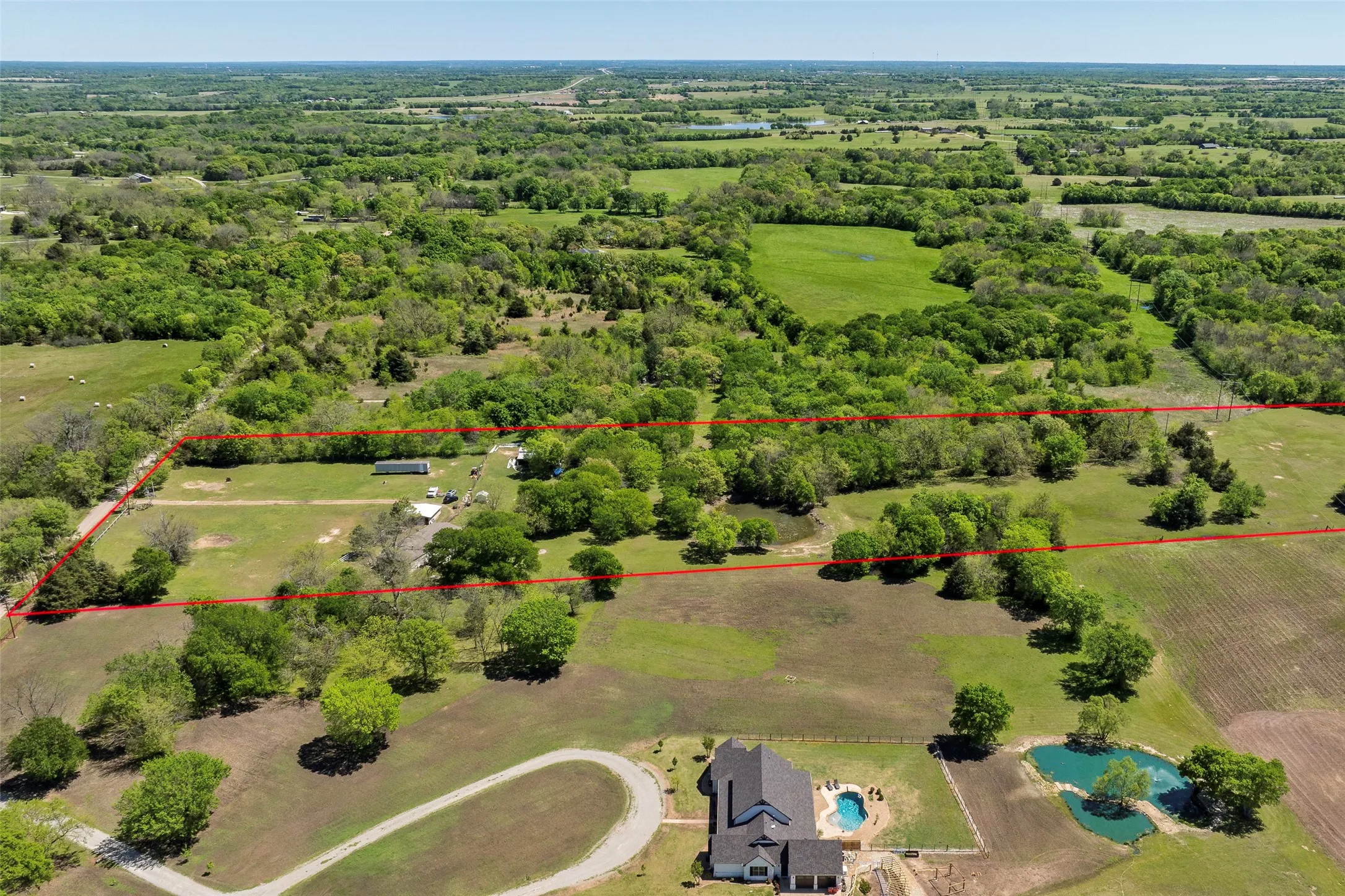 Expansive acreage featuring mature trees, open clearings, and a substantial pond