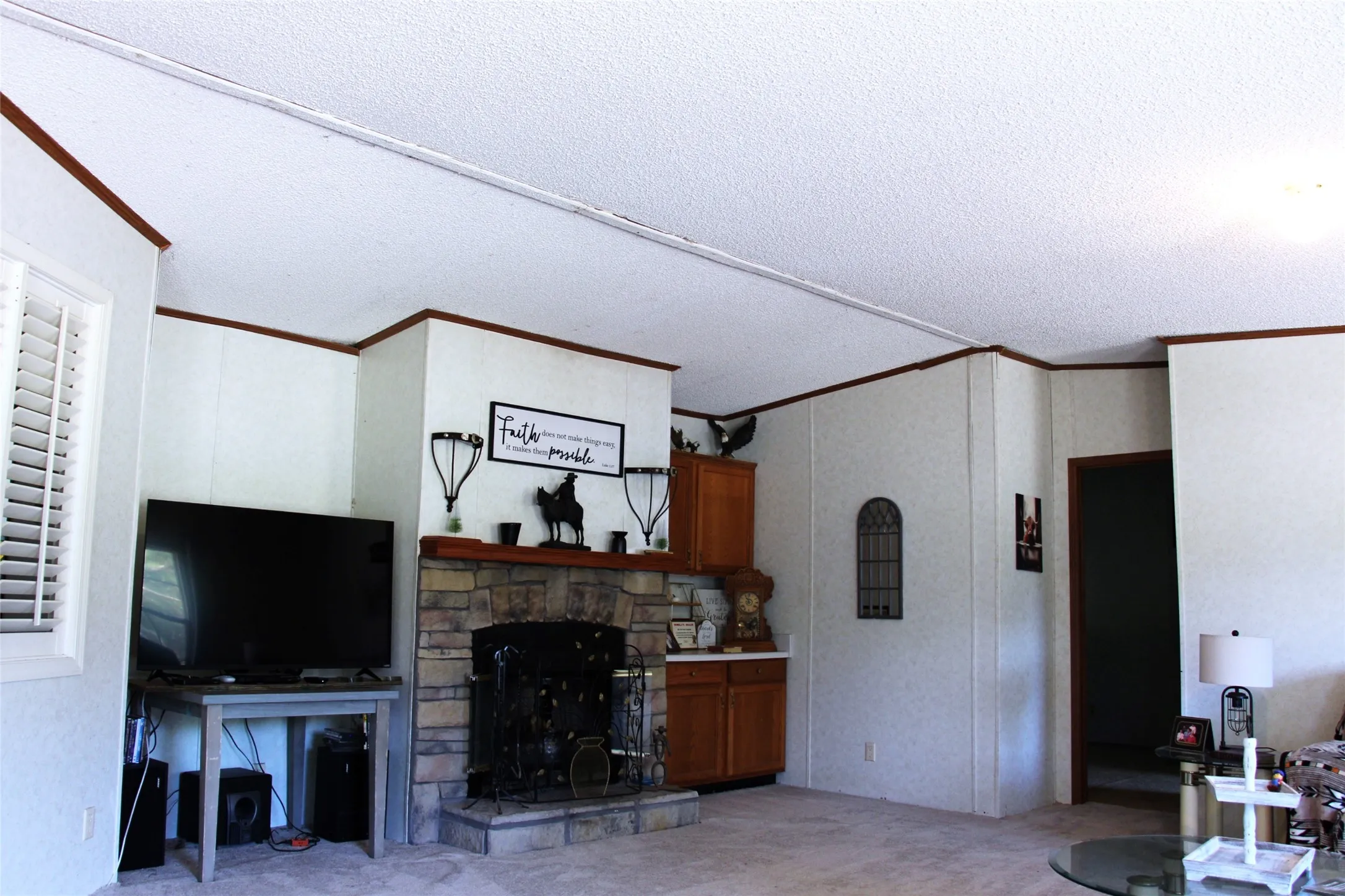 Stone-faced fireplace with a dark metal fire screen and wood mantel