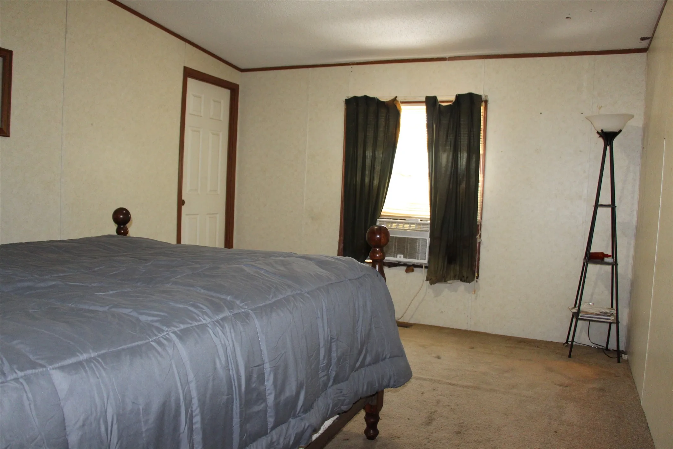 Neutral tone wall panels with dark wood trim, white interior door, and window with dark drapes