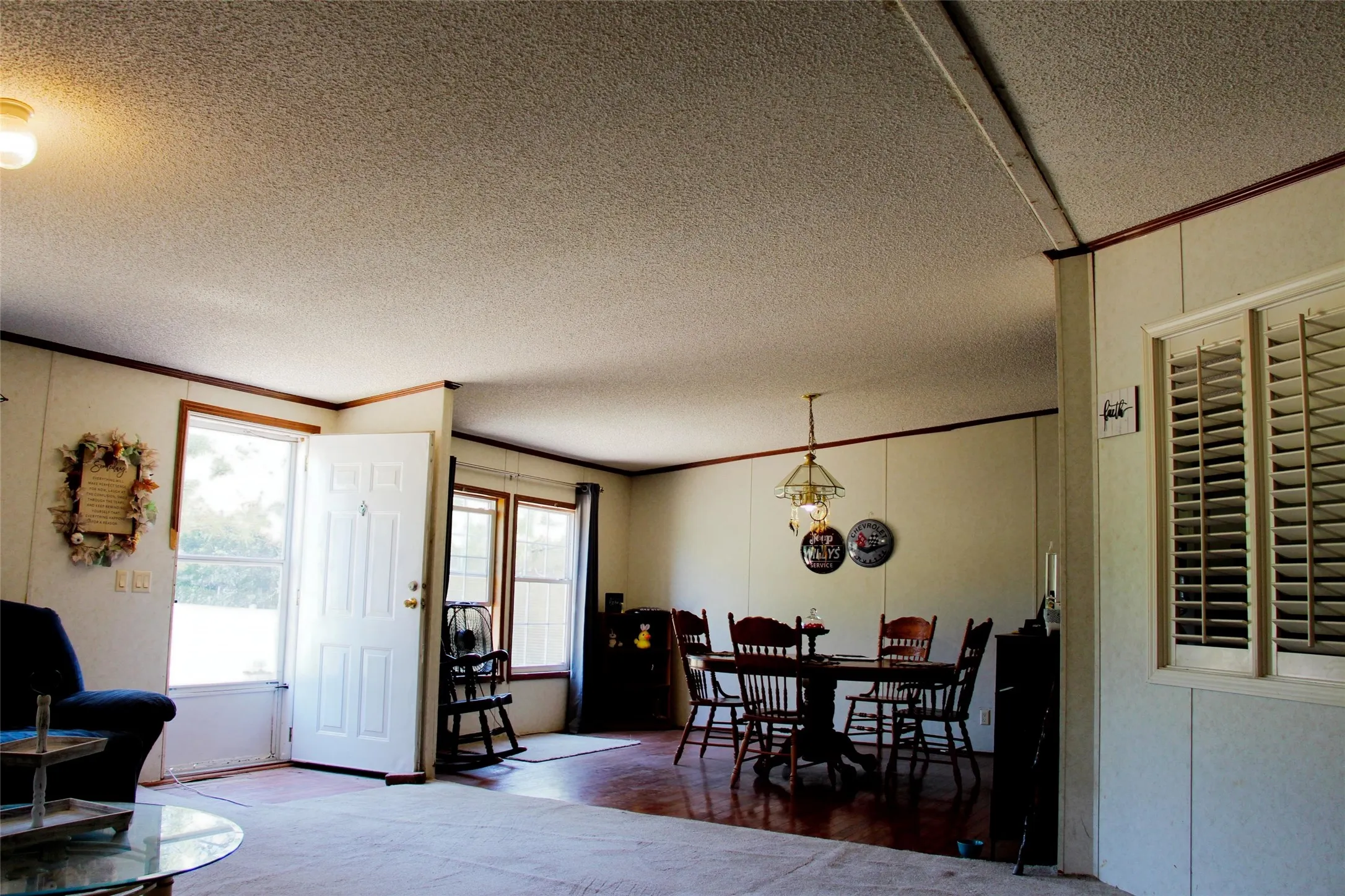 Interior space featuring light paneling walls with dark trim, a front entry door with a storm door, and multiple windows