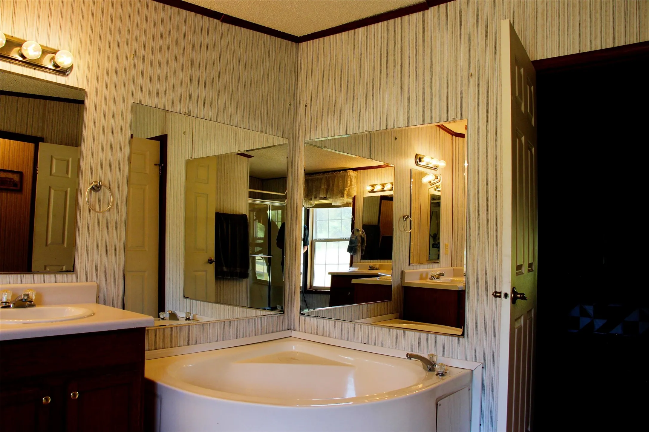 Bathroom featuring a corner soaking tub, dual vanity with undermount sinks, and wall-mounted mirrors