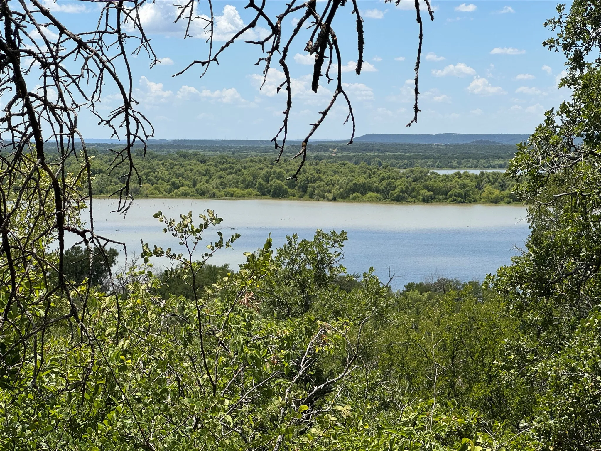 Expansive water feature bordered by dense woodlands and a distant tree line, all under a vast sky