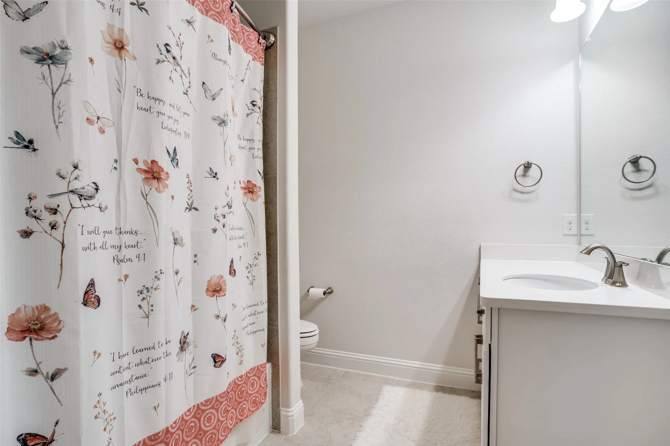 Bathroom featuring a single vanity with a white countertop and integrated sink, brushed nickel faucet, and overhead lighting