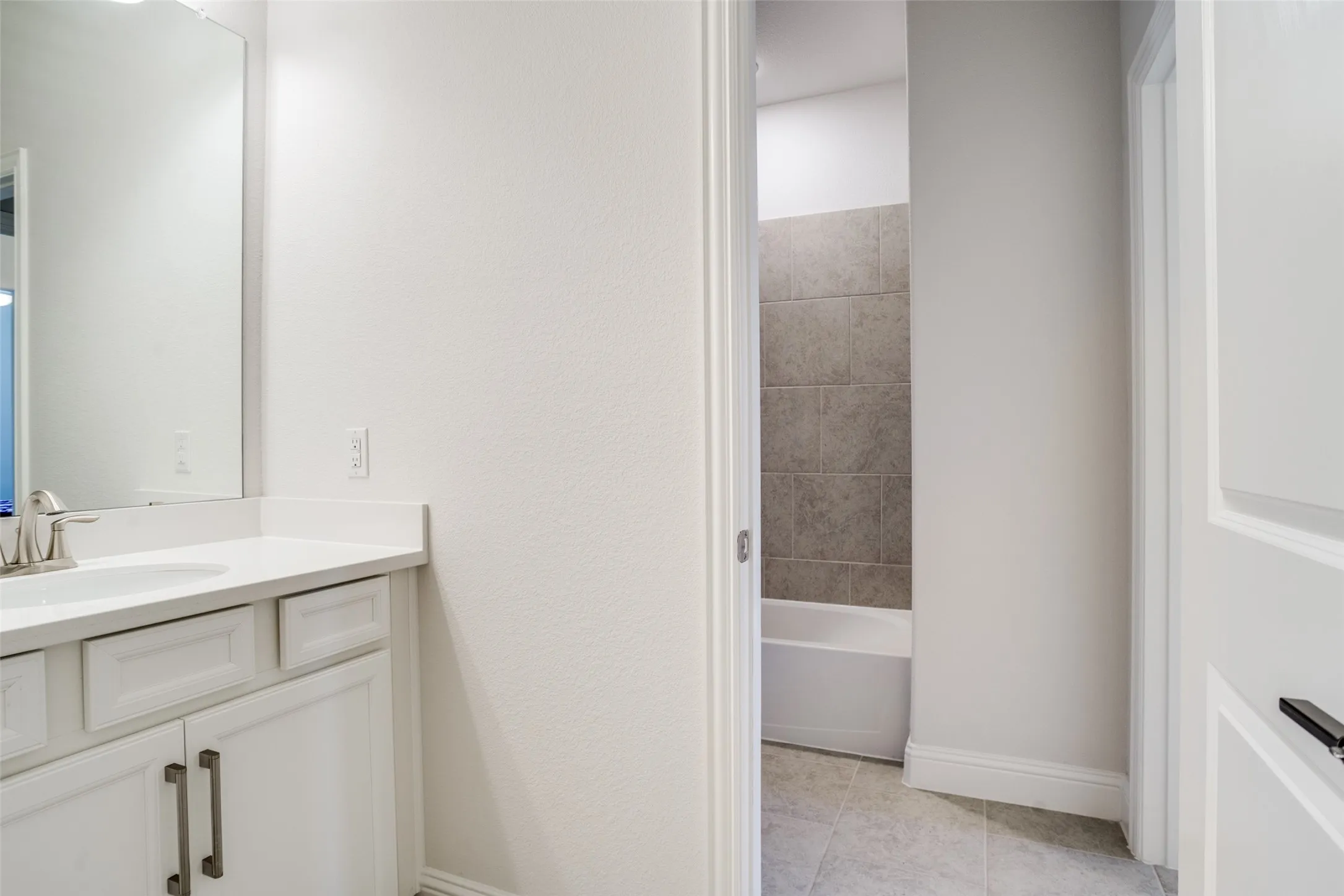 Bathroom vanity with white cabinetry, a light-colored countertop, and a rectangular undermount sink with a chrome faucet