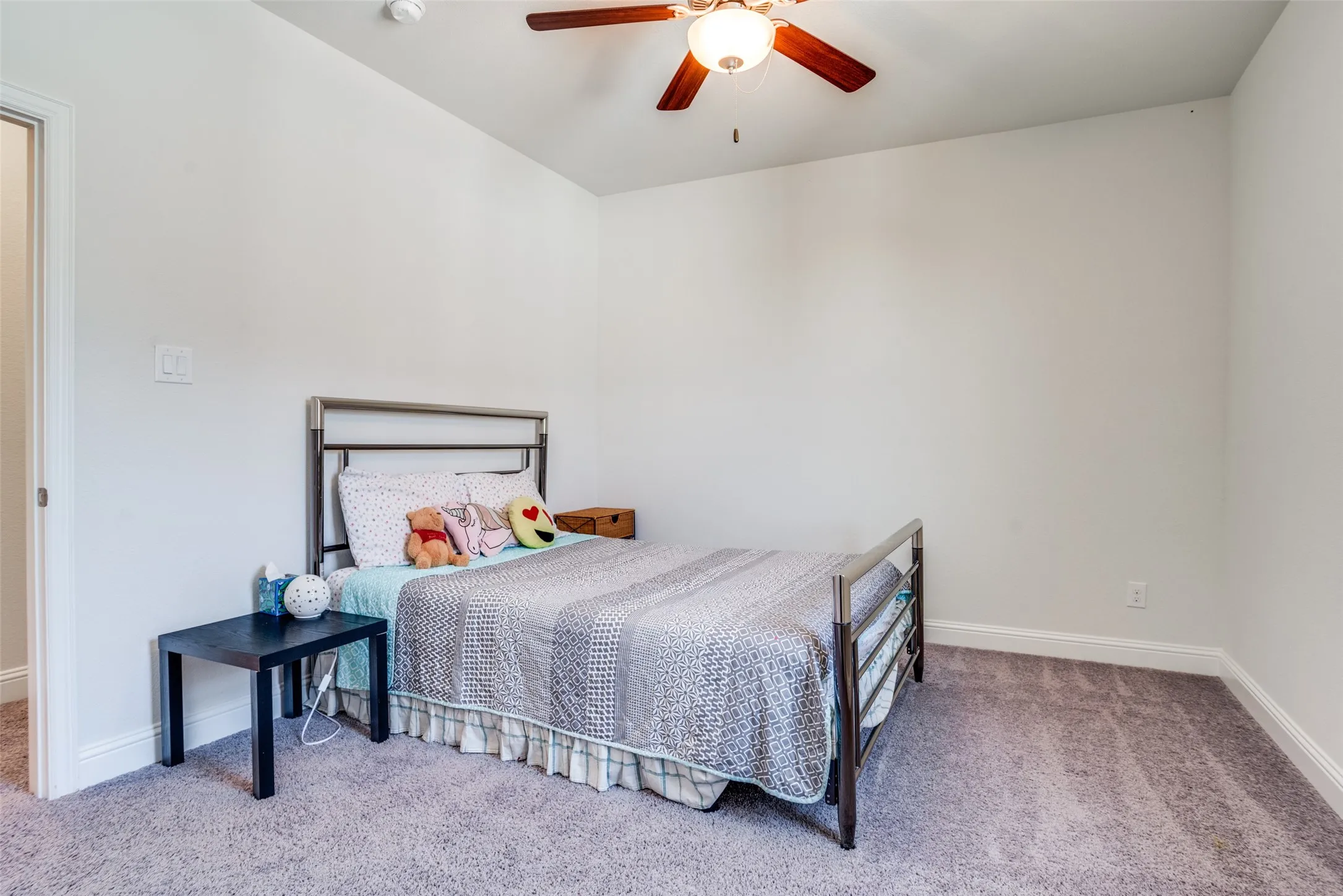 Carpeted bedroom featuring white walls and a ceiling fan with light fixture