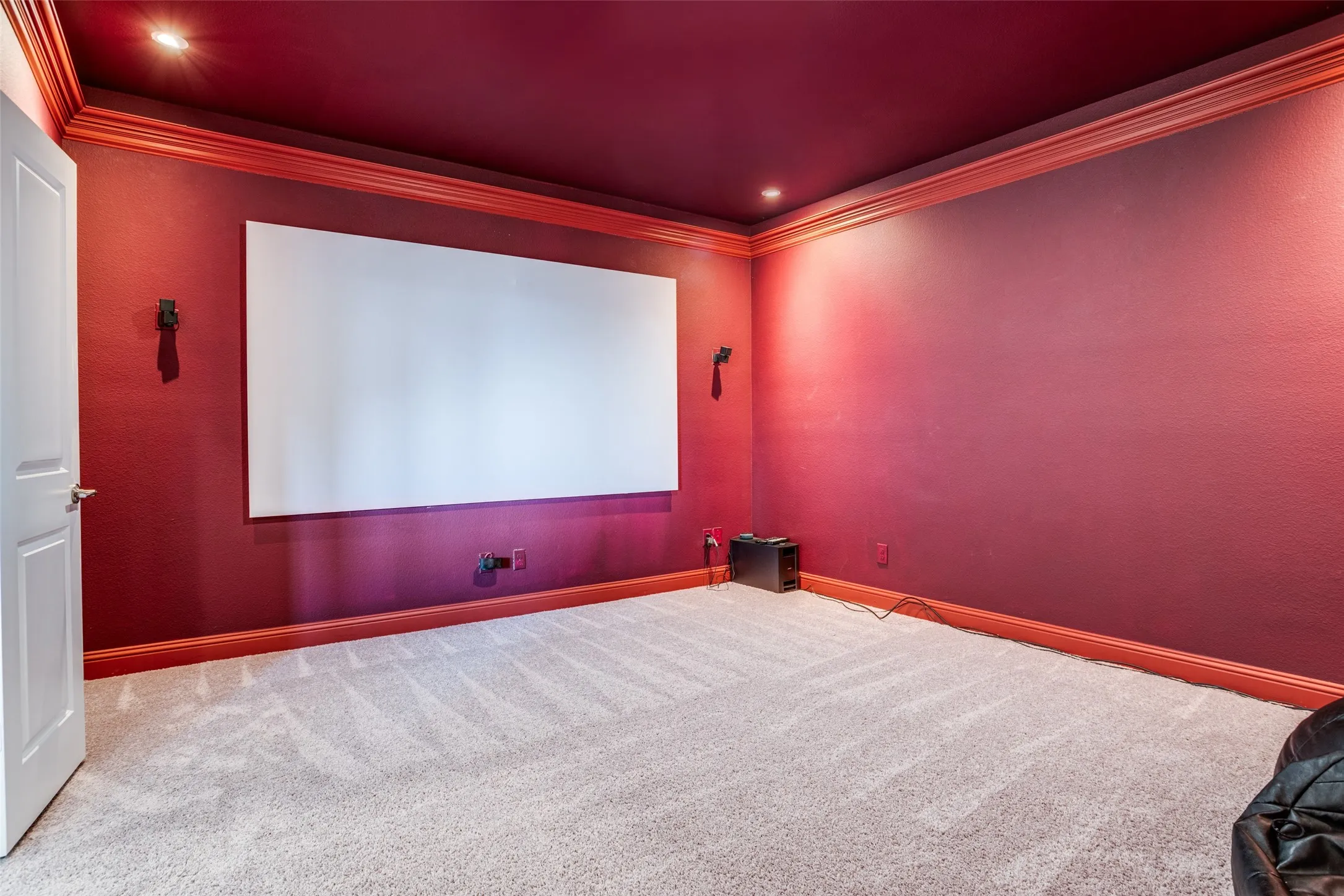 Room featuring a large projection screen, two wall-mounted sconces, recessed ceiling lighting, and crown molding