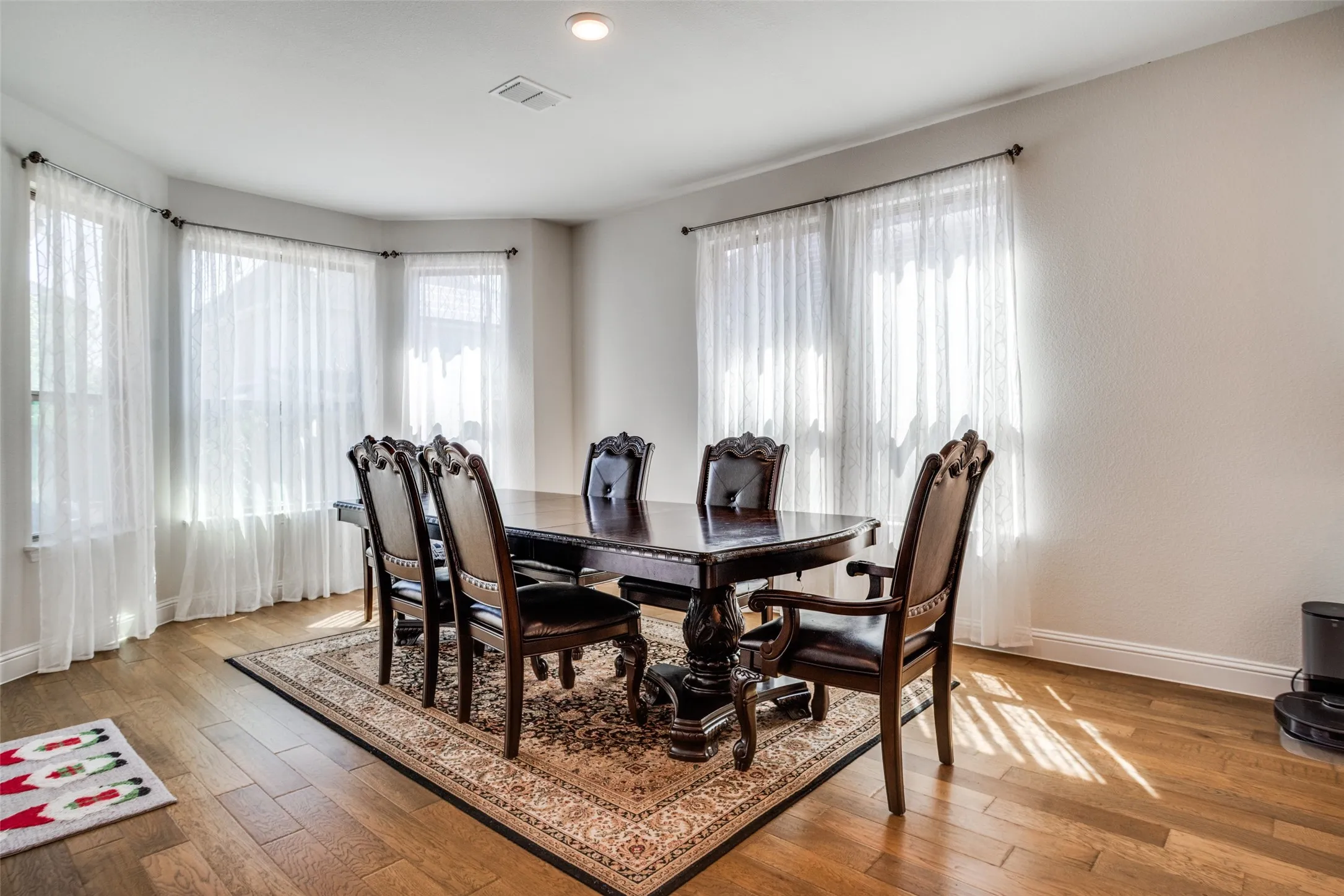 Dining area with bay windows, recessed lighting, wood-finish flooring, and crown molding