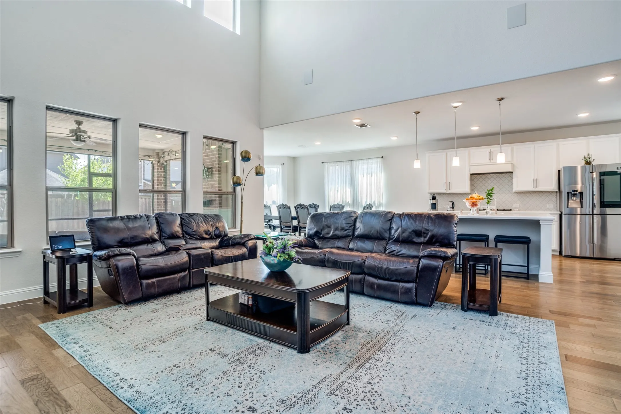 Spacious living area featuring high ceilings, wood-finish flooring, and multiple windows