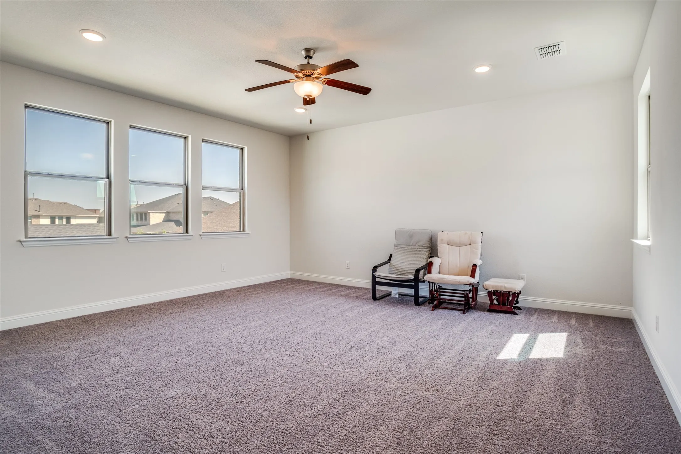 Spacious room featuring neutral carpet flooring and white walls