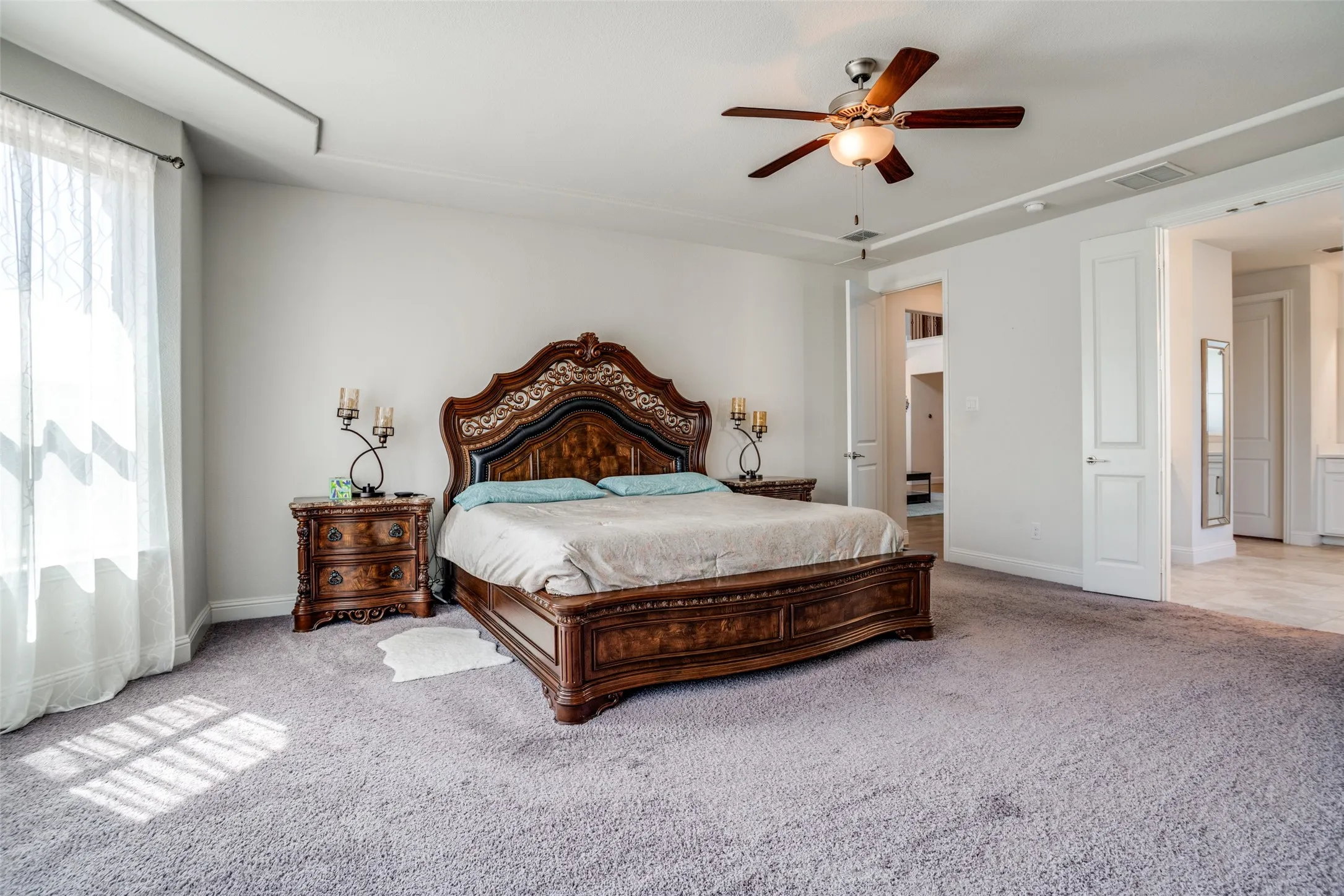 Spacious room featuring light gray walls, a tray ceiling, and light gray carpeting