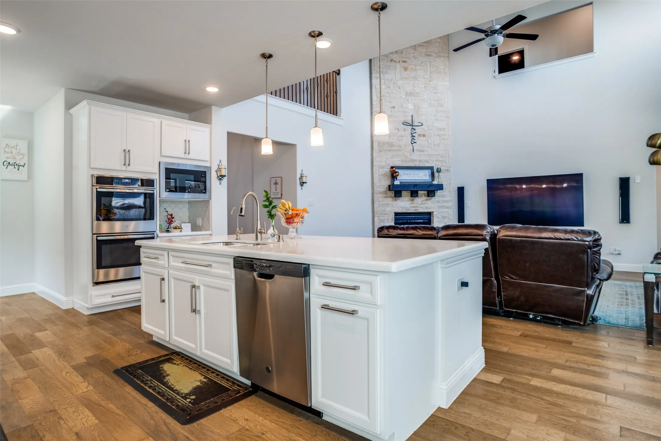 Gourmet kitchen featuring a large island with sink, white cabinetry, stainless steel appliances, and wood-finish flooring