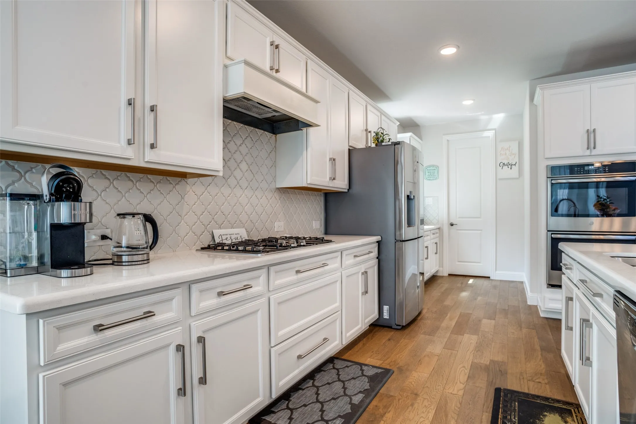 Kitchen featuring white shaker cabinetry, stainless steel appliances, a gas cooktop, white countertops, and wood-finish flooring