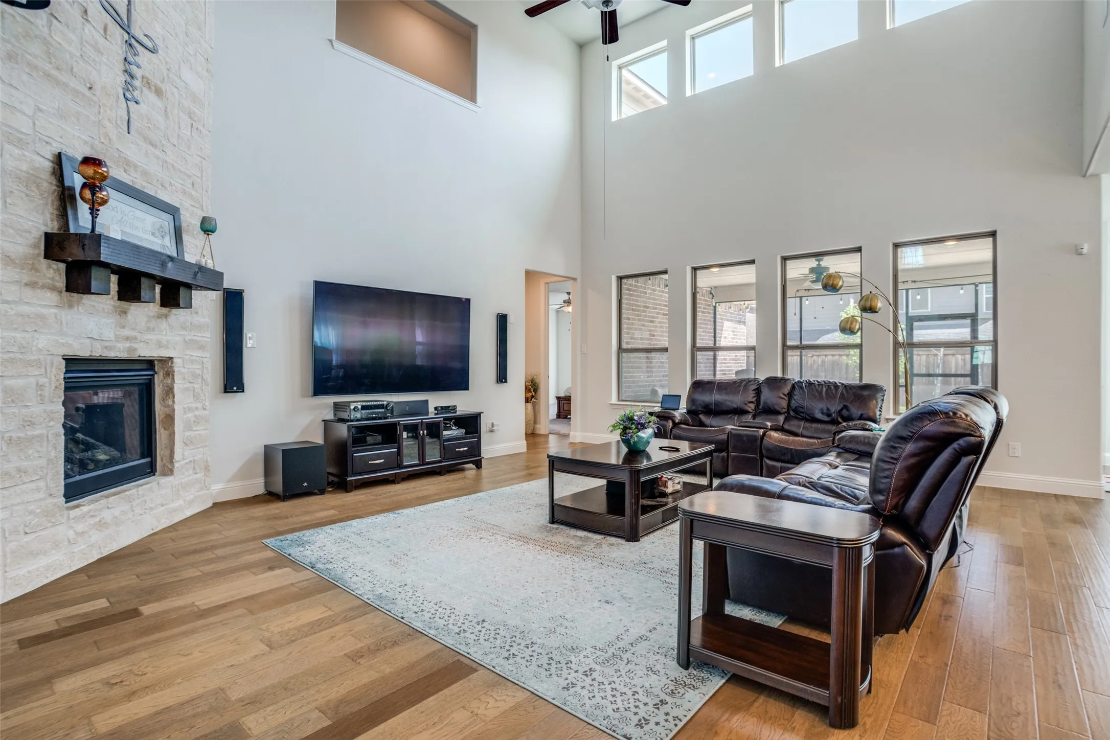 Living area featuring vaulted ceilings, a stone-clad fireplace with a dark wood mantel, and wood-finish flooring