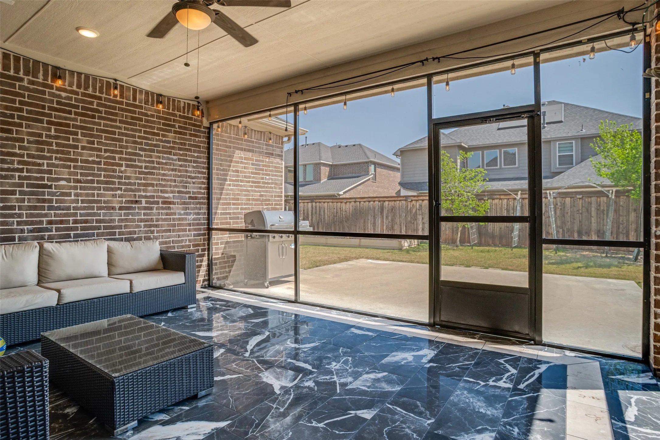 Screened patio featuring dark brick wall, black marble-look flooring, recessed lighting, and a ceiling fan