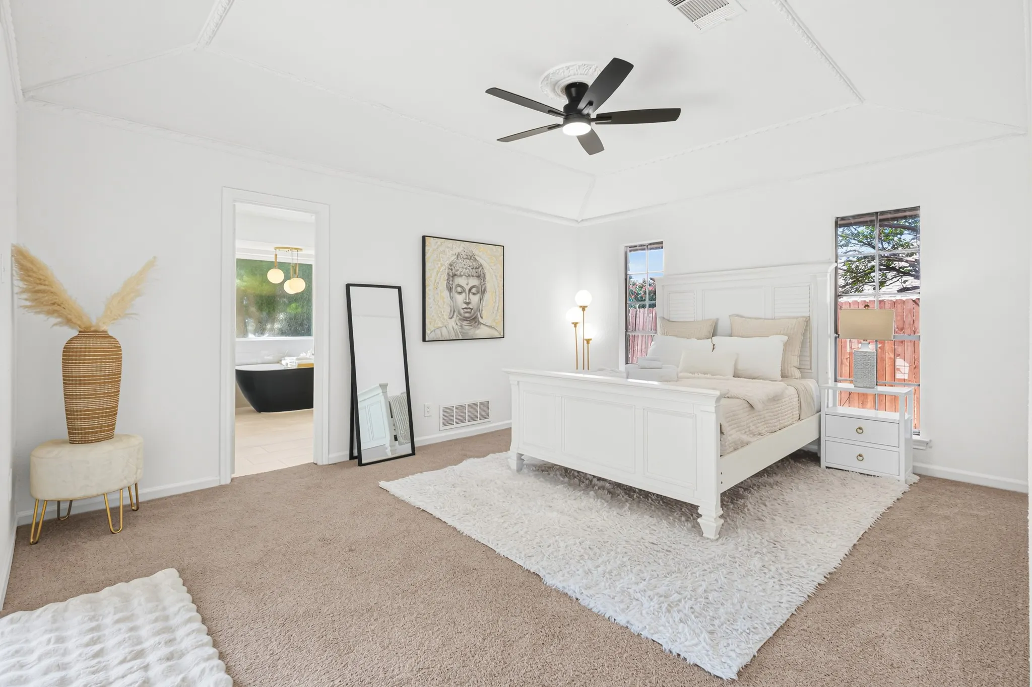 Spacious primary bedroom featuring neutral carpeting, a ceiling fan, and abundant natural light from multiple windows