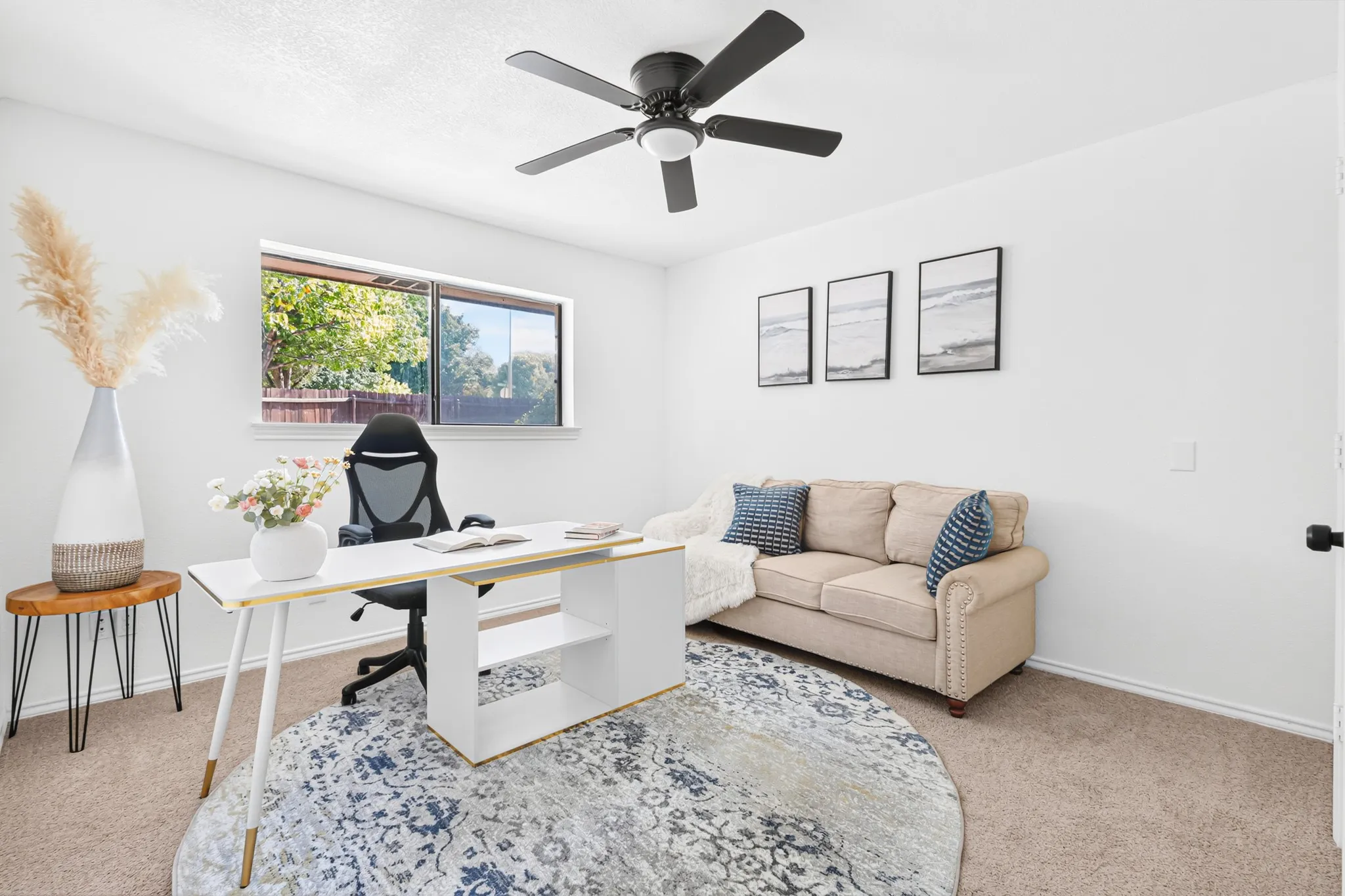 Modern home office featuring a light wood desk with integrated storage, ergonomic black office chair, and abundant natural light from dual windows